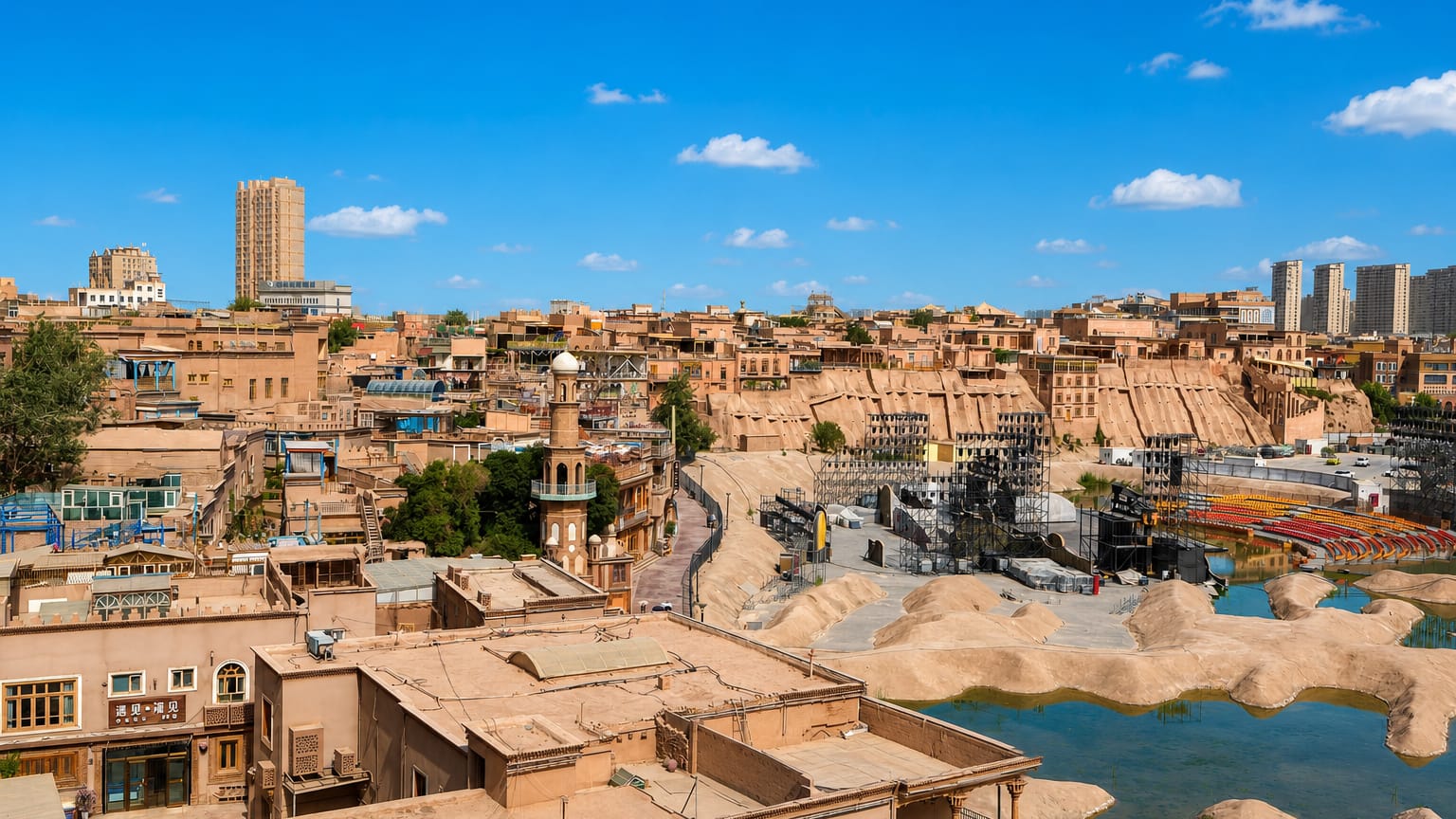 Earthen Old Town buildings and a minaret in Kashgar with modern towers rising beyond under a clear blue sky.