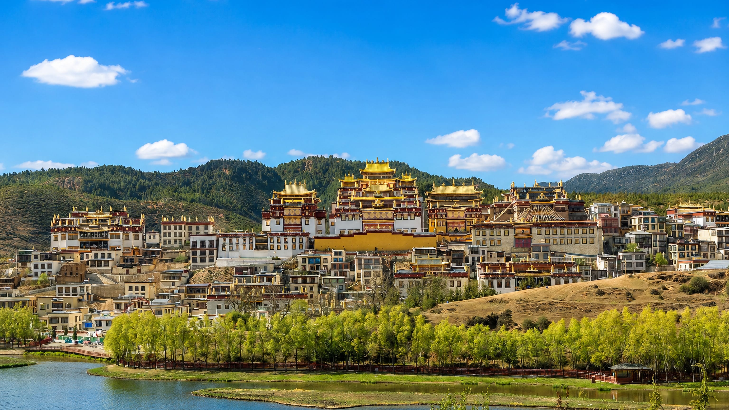 Tibetan monastery with golden roofs rising above a lake at Shangri-La, Yunnan, China.