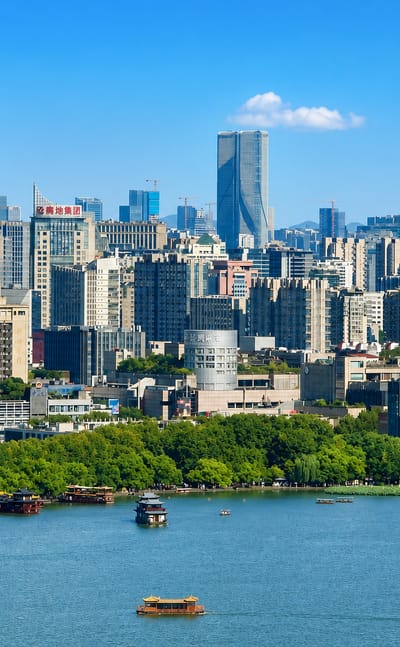 Hangzhou's modern skyline rising behind West Lake with traditional pleasure boats on the water