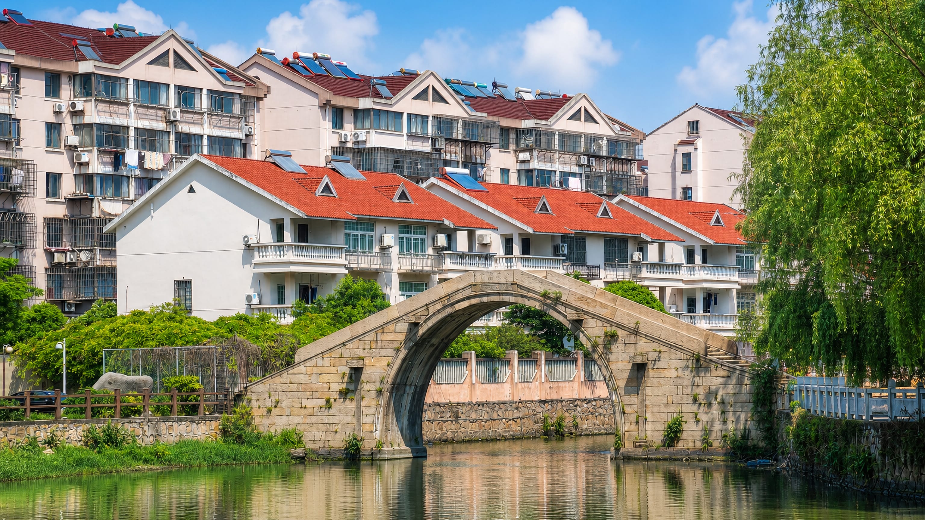 Old stone arch bridge over a canal below red-roofed houses in Jiashan, Jiaxing.