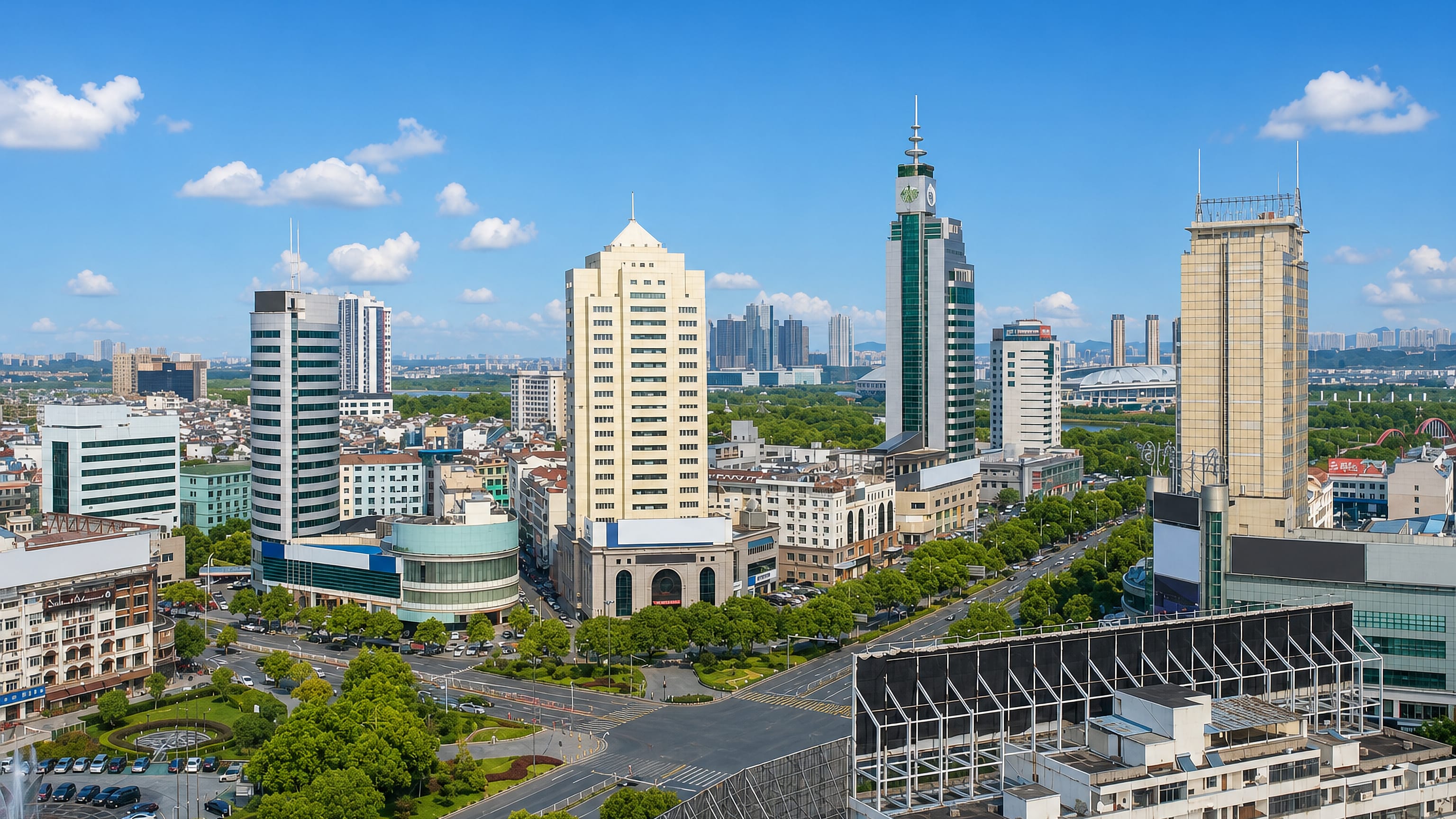 Yiwu's downtown skyline in Zhejiang, with mid-rise towers, a green clock tower and a tree-lined boulevard.