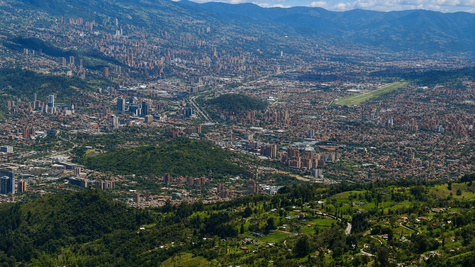 Panoramic aerial of the Aburra Valley with Medellin's cityscape climbing the slopes above the El Poblado district