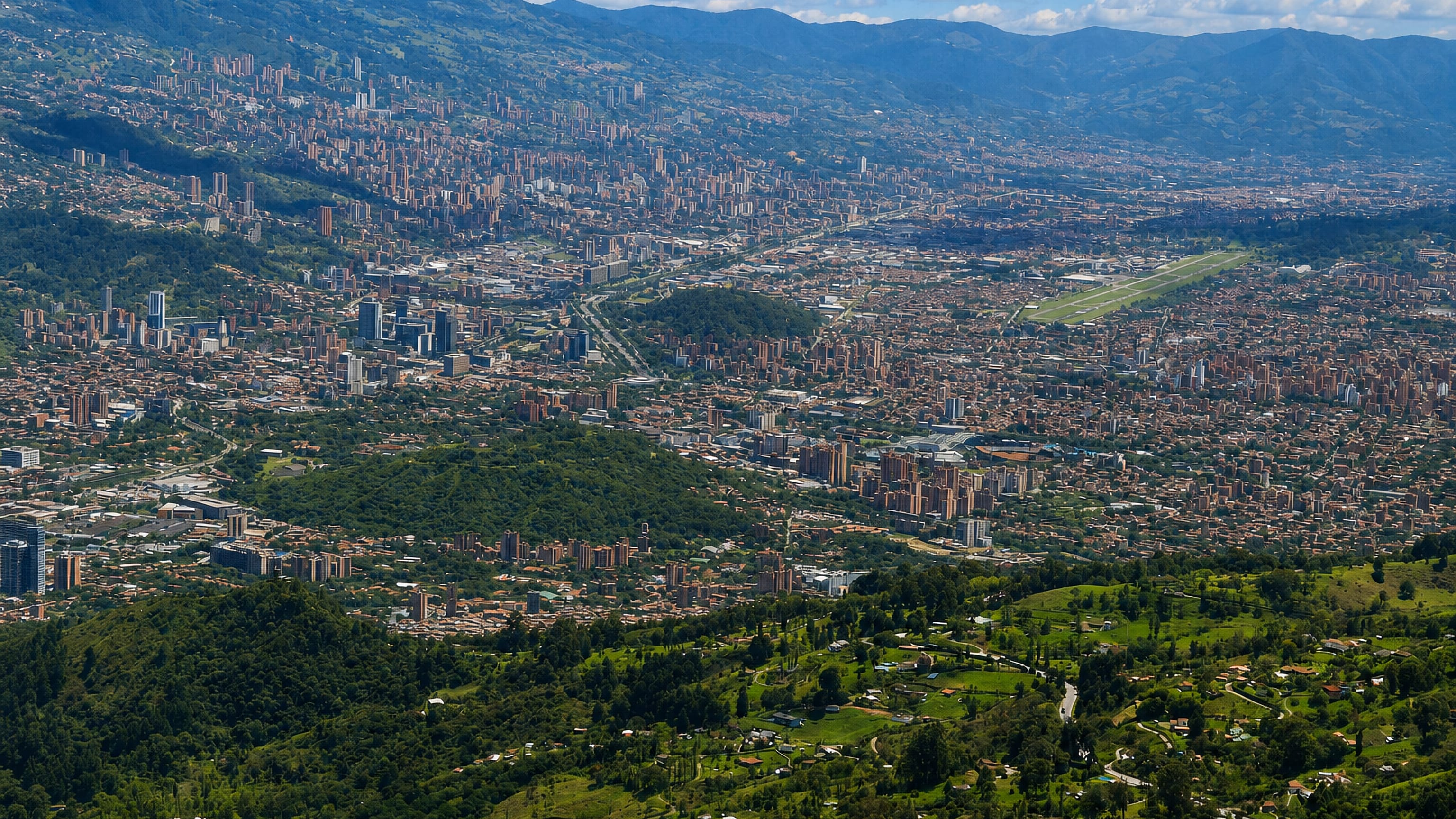 Panoramic aerial of the Aburra Valley with Medellin's cityscape climbing the slopes above the El Poblado district