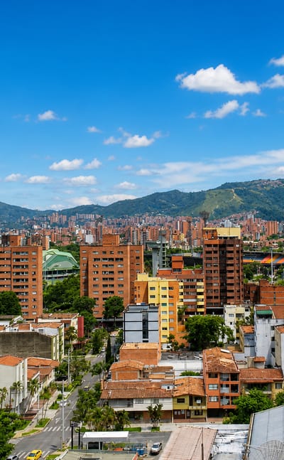 Dense red-brick mid-rises and a stadium complex fill the Aburra Valley below Andean peaks in Medellin's Laureles-Estadio district.