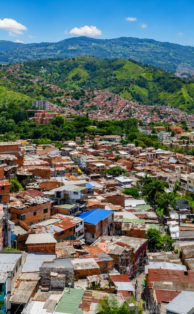 Dense hillside barrio of red-brick houses climbing green mountains in San Javier, Medellin