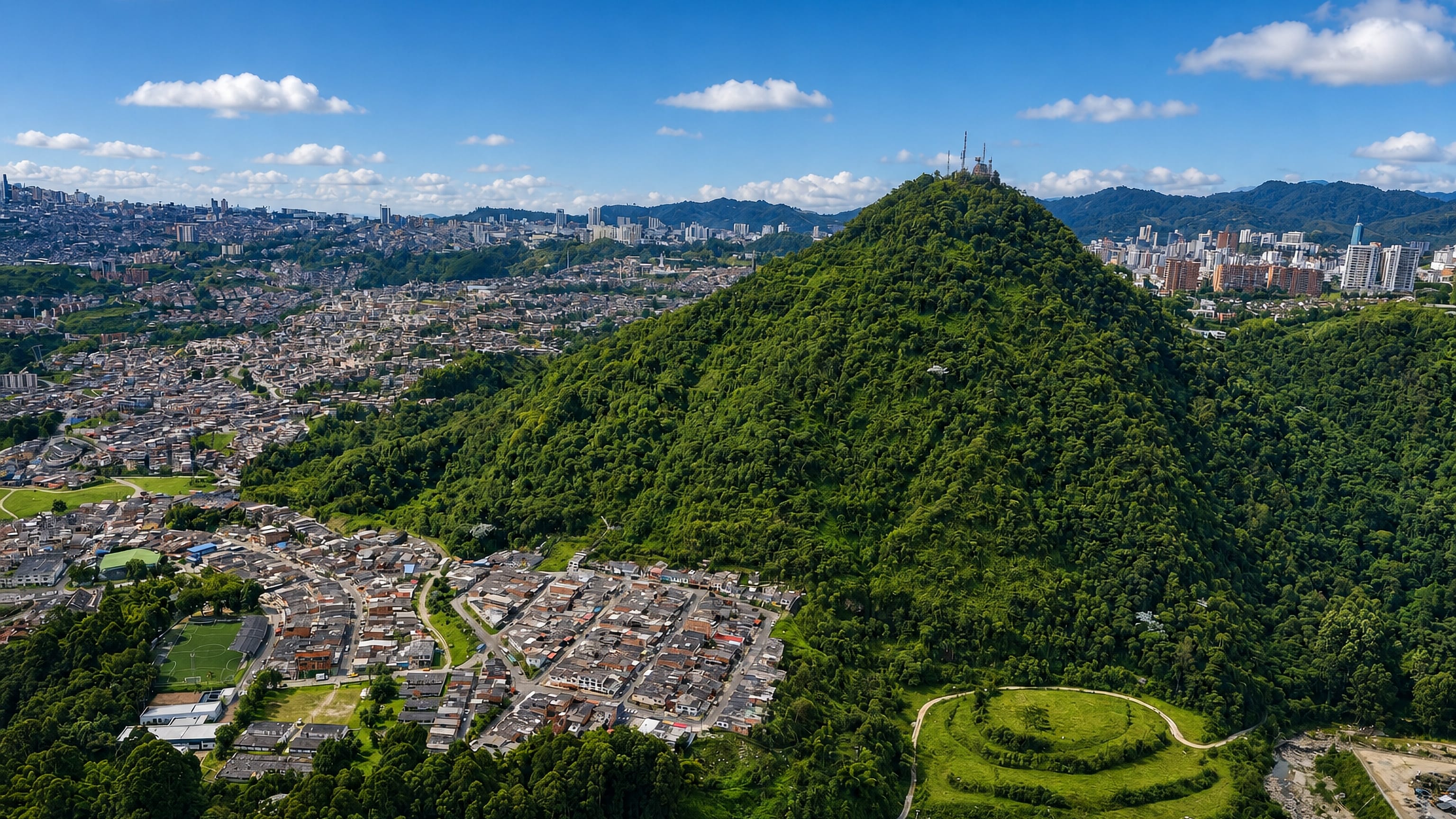 Aerial view of Manizales, Colombia: a forested conical hill rising between ridge-top neighbourhoods and high-rises.