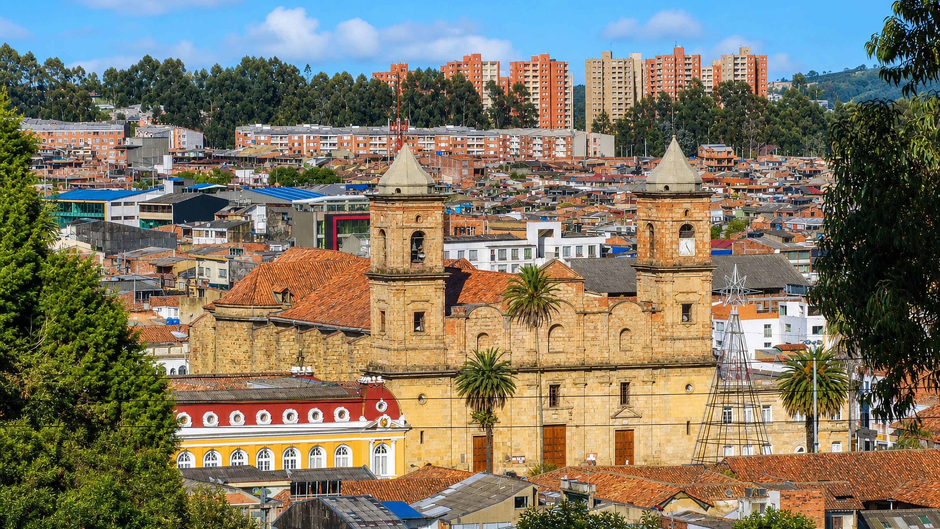 Twin sandstone towers of Zipaquirá's cathedral rising above tiled roofs and hillside housing in Colombia.