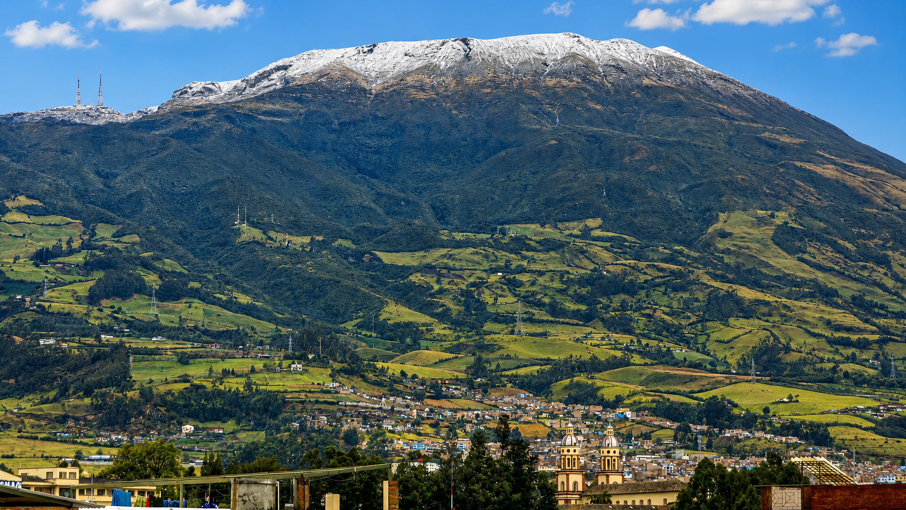 Galeras volcano rising over Pasto, Colombia, with the twin towers of a colonial church among the rooftops