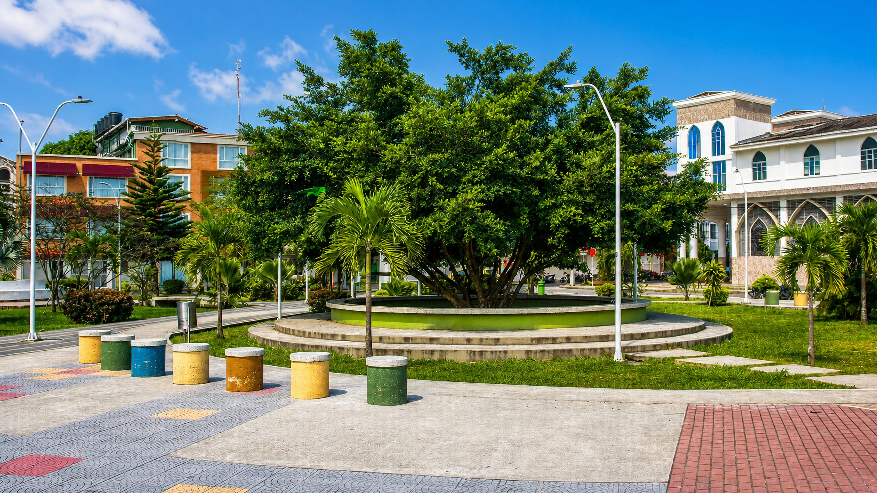 Patterned plaza paving and a shade tree beside a white arched church in Tumaco, Narino.