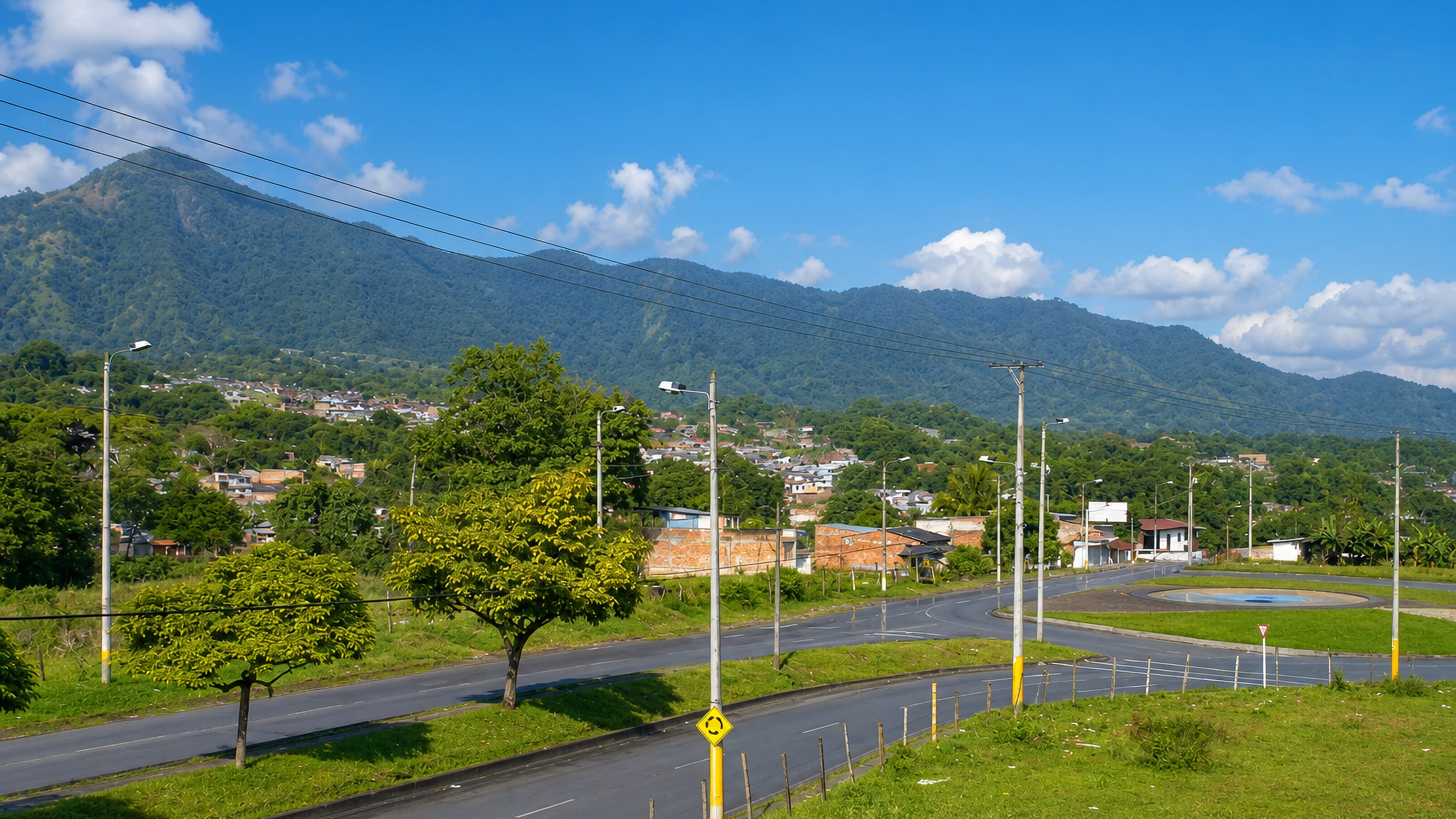 Ibagué's outskirts: a curving road and roundabout below forested Andean ridges in Tolima, Colombia.