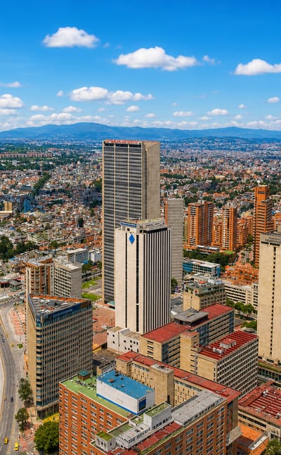 Aerial skyline of downtown Bogotá with clustered high-rise towers and the Andean mountains rising behind
