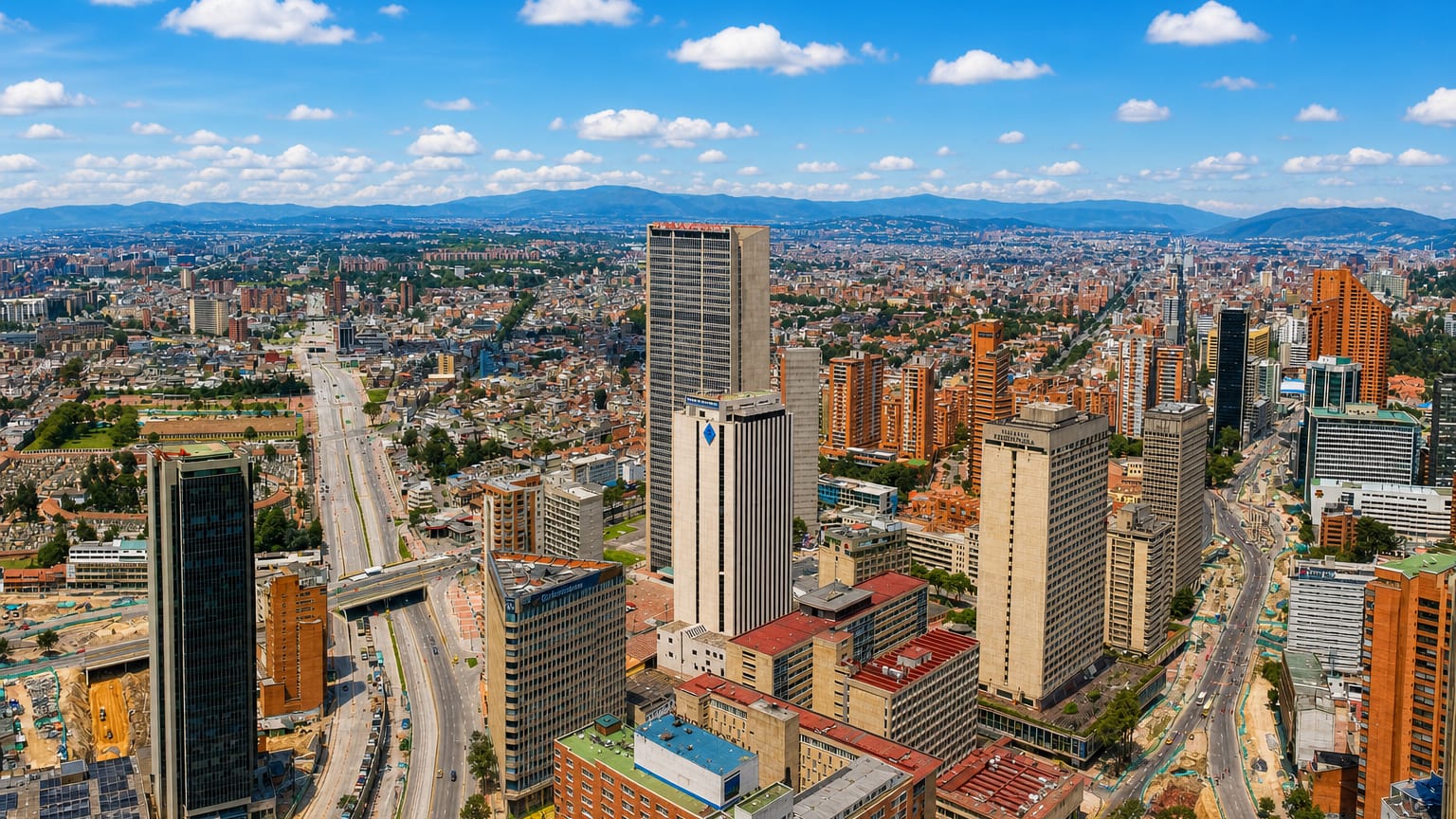 Aerial skyline of downtown Bogotá with clustered high-rise towers and the Andean mountains rising behind