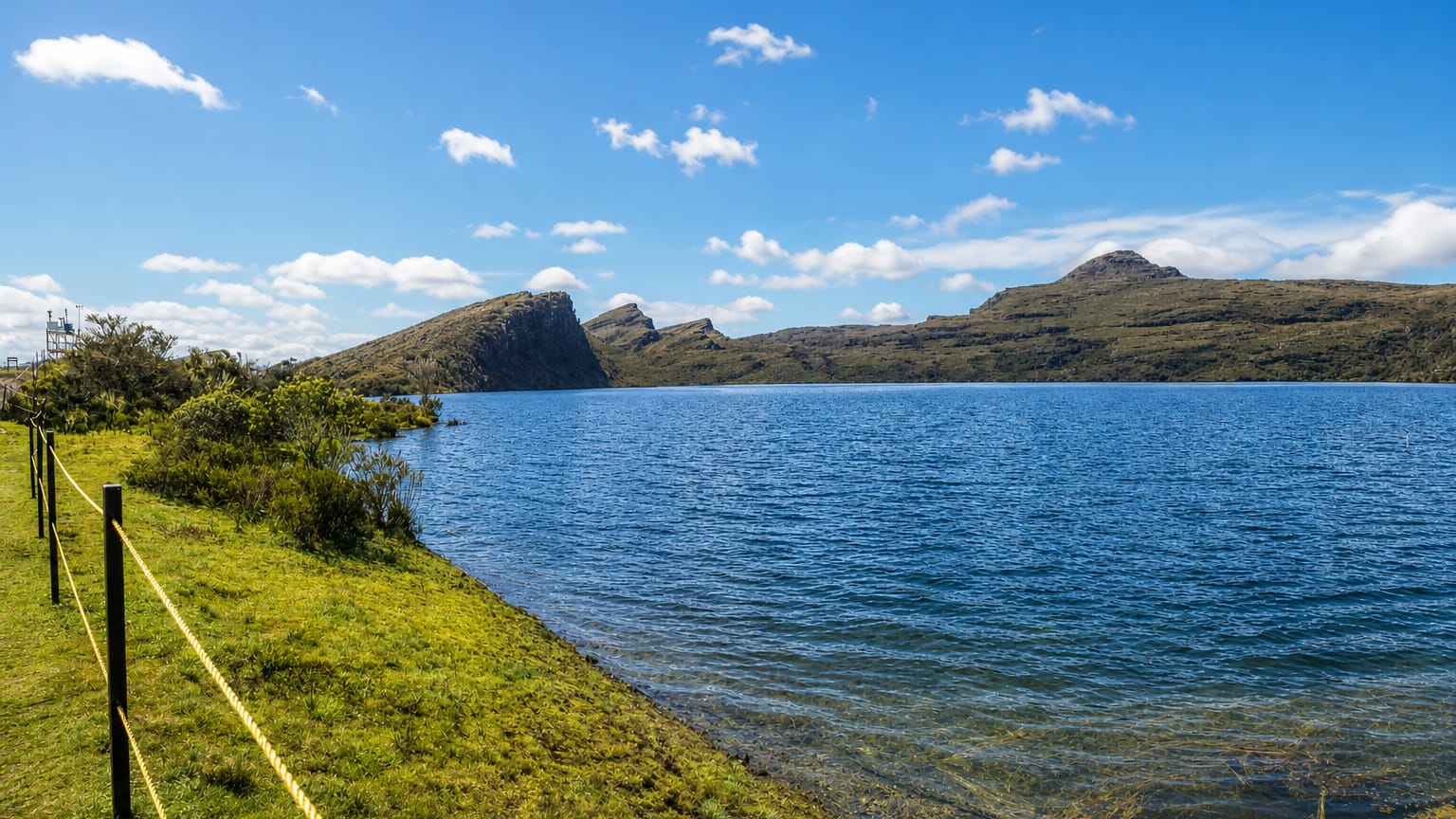 A high-altitude paramo lake ringed by grassy moorland hills in the rural Sumapaz locality of Bogota