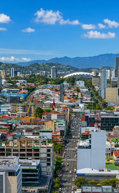 Aerial view of San José, Costa Rica, colorful rooftops filling a mountain-ringed valley with the national stadium.