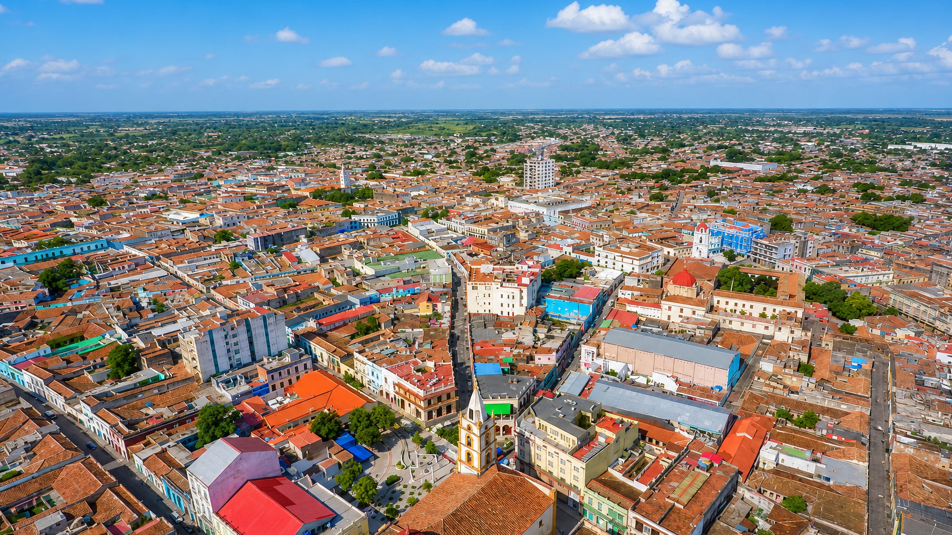 Aerial view over Camaguey, Cuba, a dense grid of terracotta rooftops and colonial church towers.