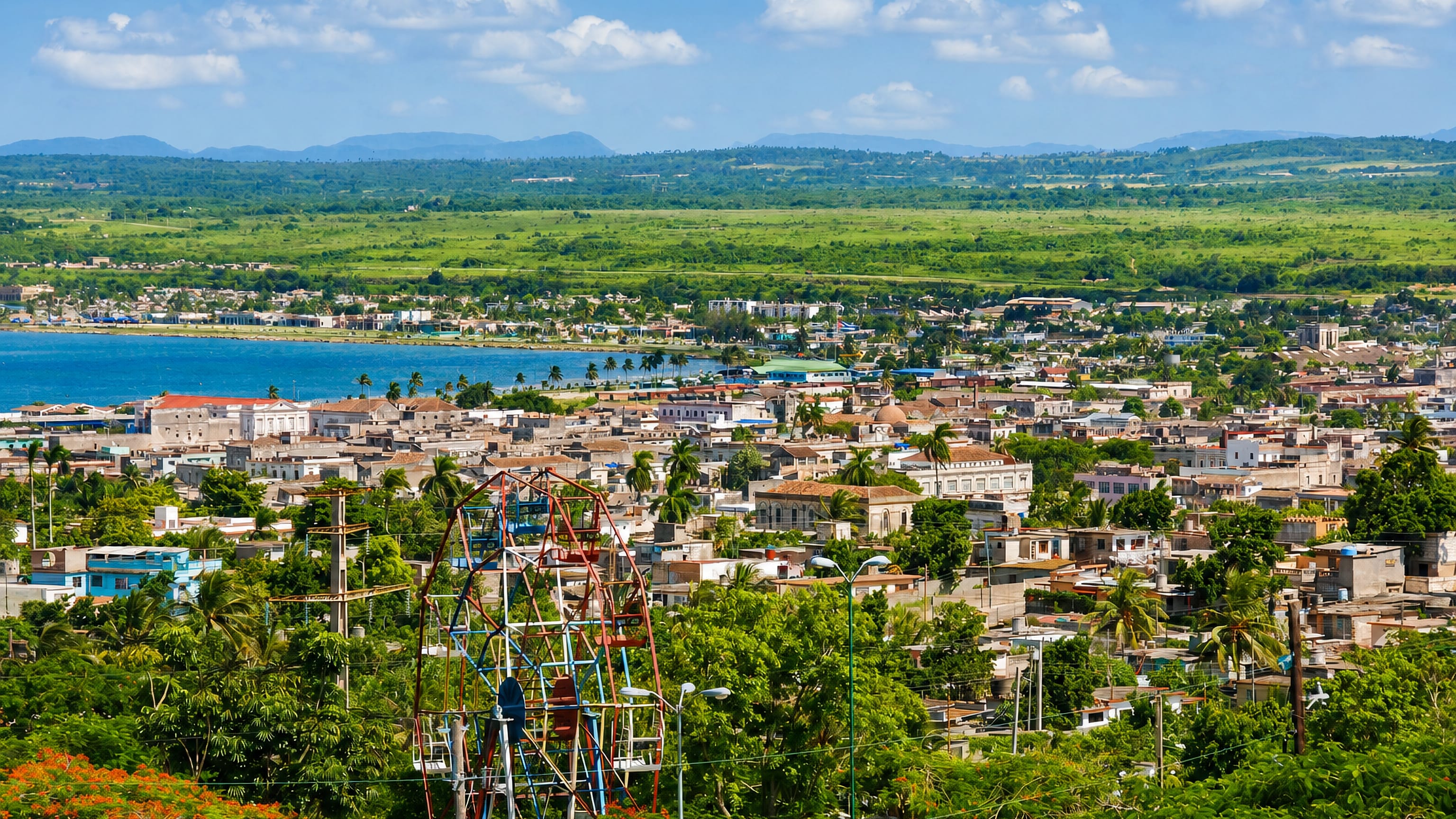 Hillside view over Matanzas, Cuba, with low-rise streets, palms and the blue bay beyond.