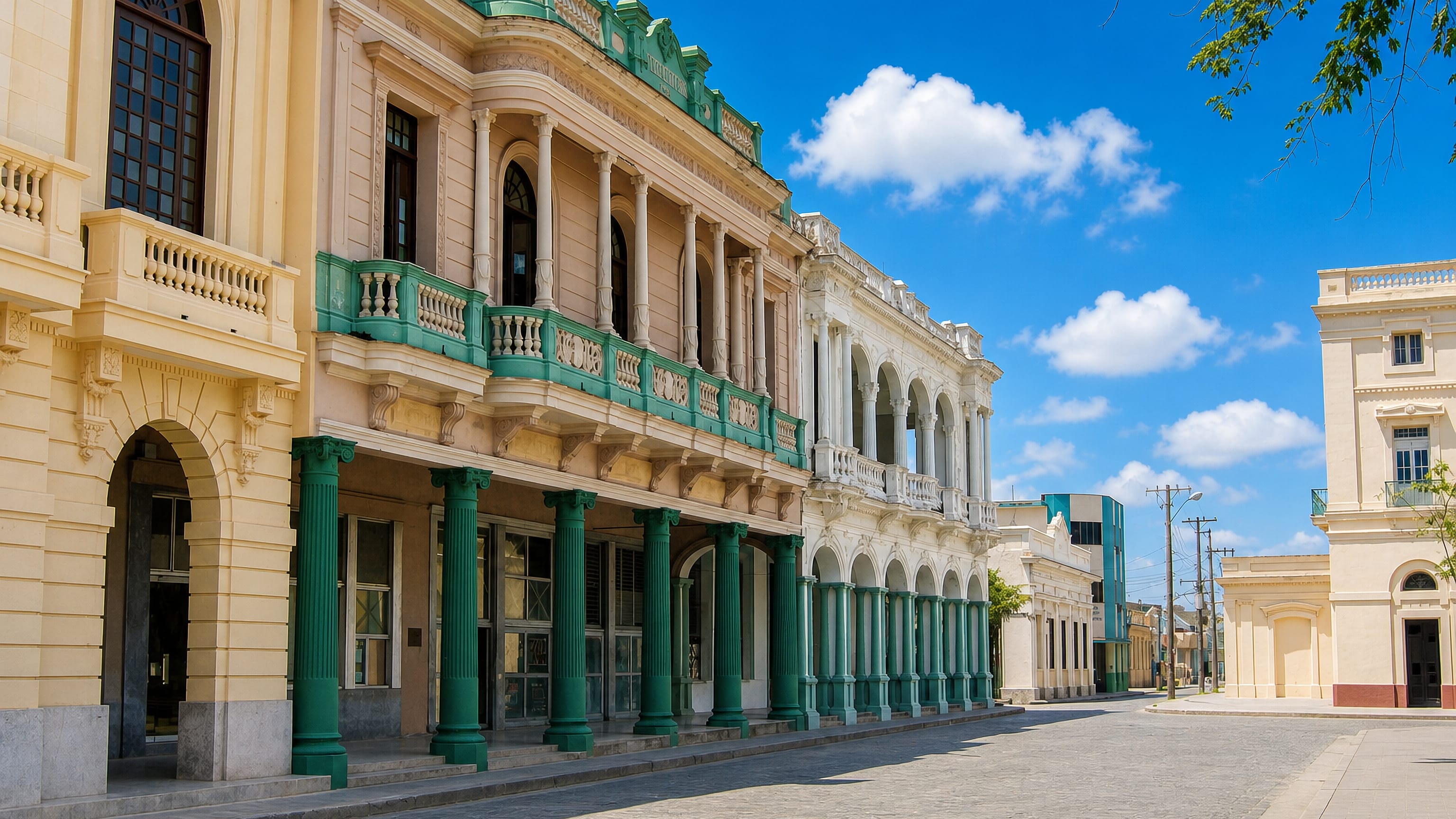 Colonnaded colonial buildings with green columns lining a cobbled street off Parque Vidal in Santa Clara, Cuba.