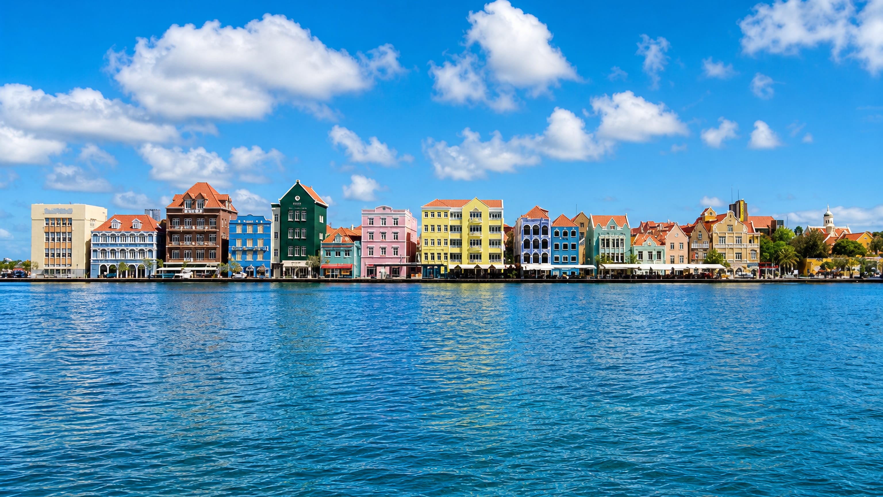 Pastel Dutch colonial facades along the Handelskade waterfront in Willemstad, Curacao, seen across Sint Anna Bay.