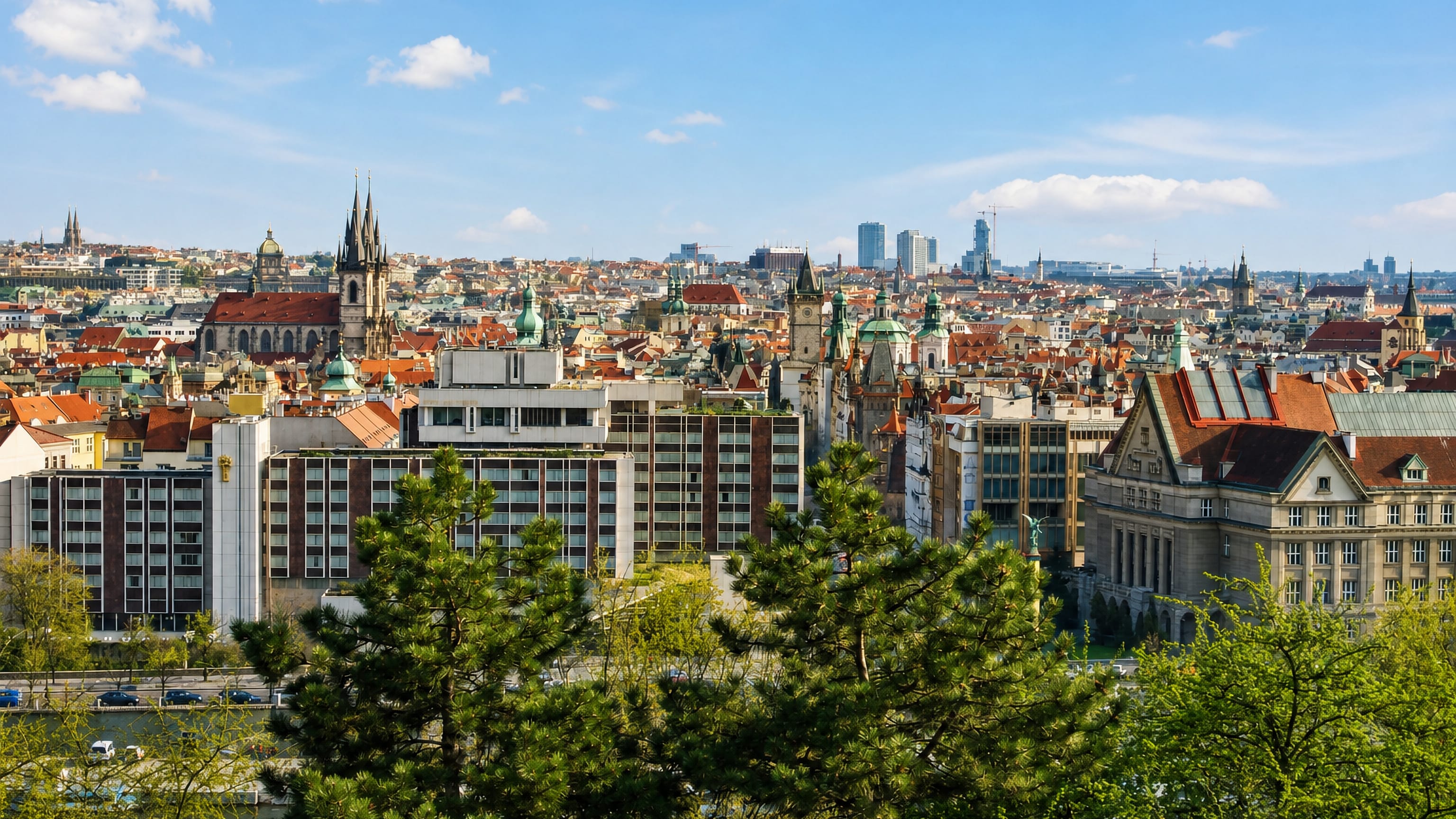 Prague rooftops and the Týn Church spires seen across the Vltava above the Josefov quarter.