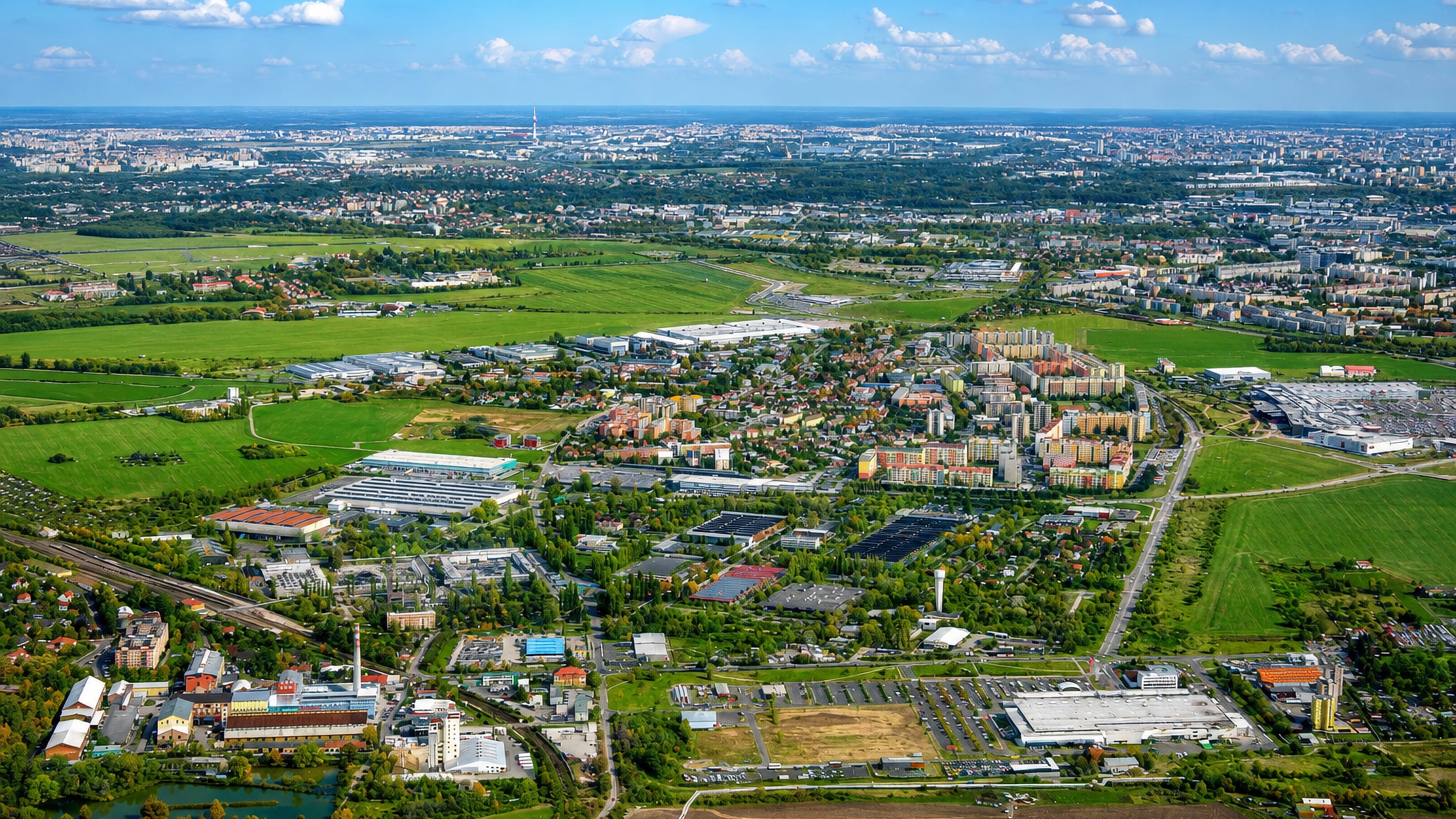 High aerial over Letňany in northern Prague, with housing blocks, retail sheds and the city skyline beyond