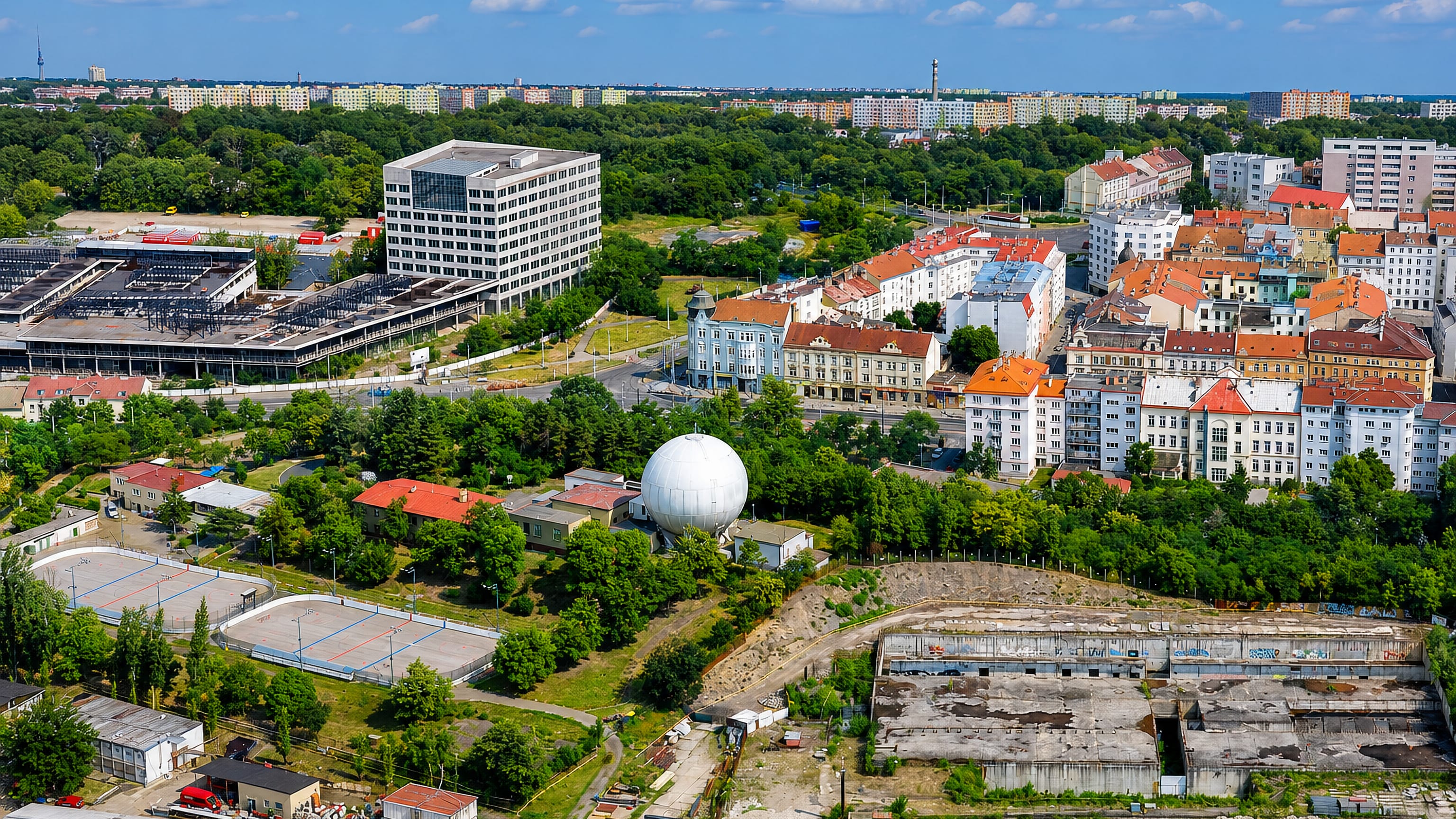 Aerial over Libeň in Prague, with panel housing, red-roofed apartment blocks and derelict industrial land.