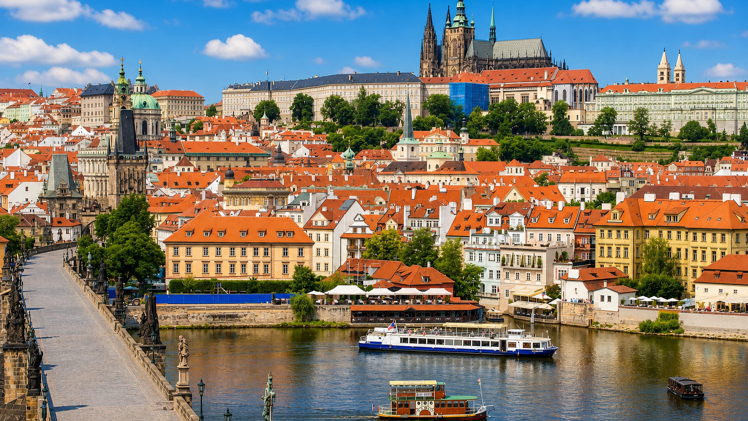 Mala Strana's red rooftops below Prague Castle and St Vitus Cathedral, seen from Charles Bridge over the Vltava.
