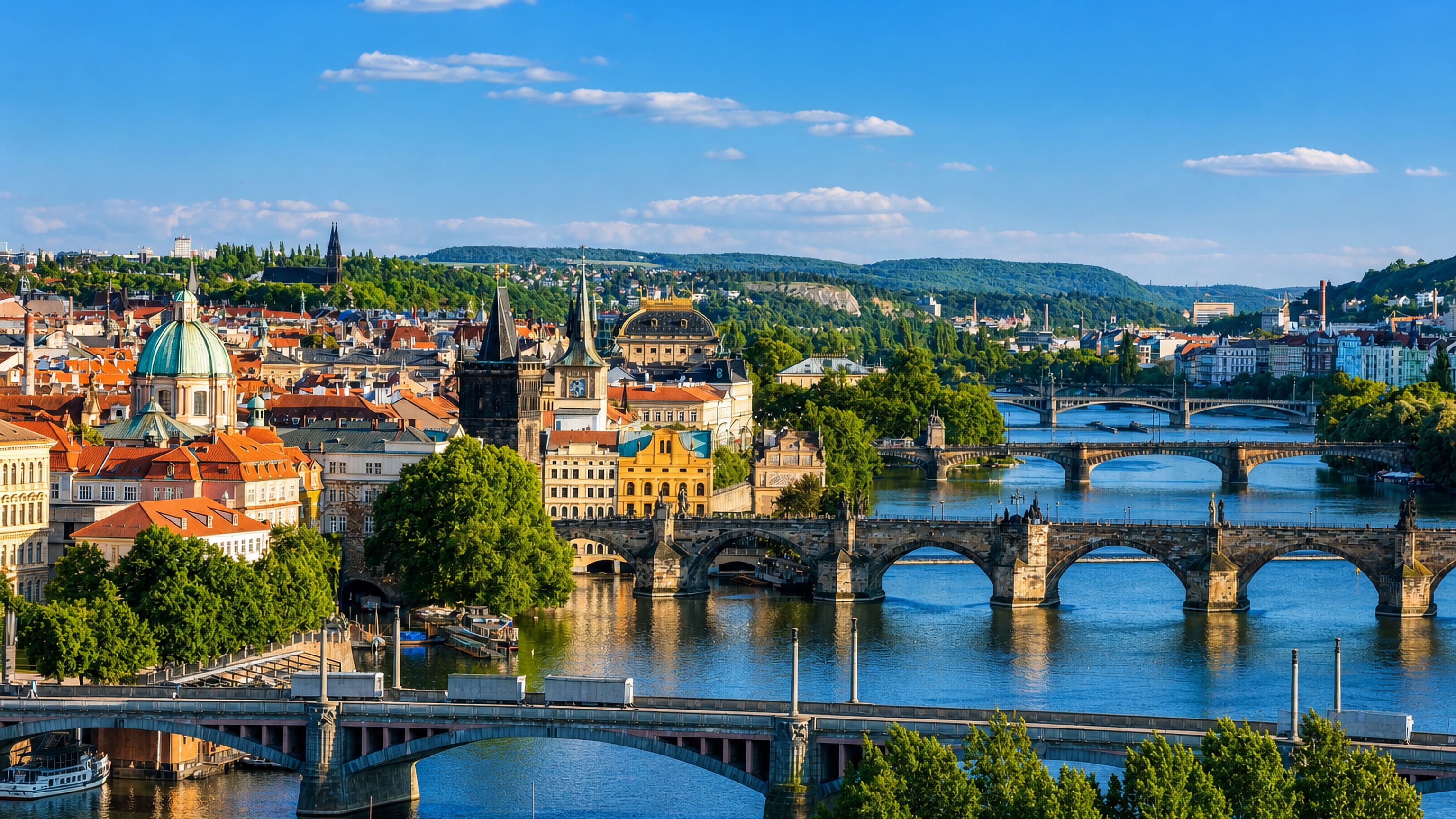 Charles Bridge and the Vltava's bridges below the red rooftops and towers of Prague 1 on a clear summer day