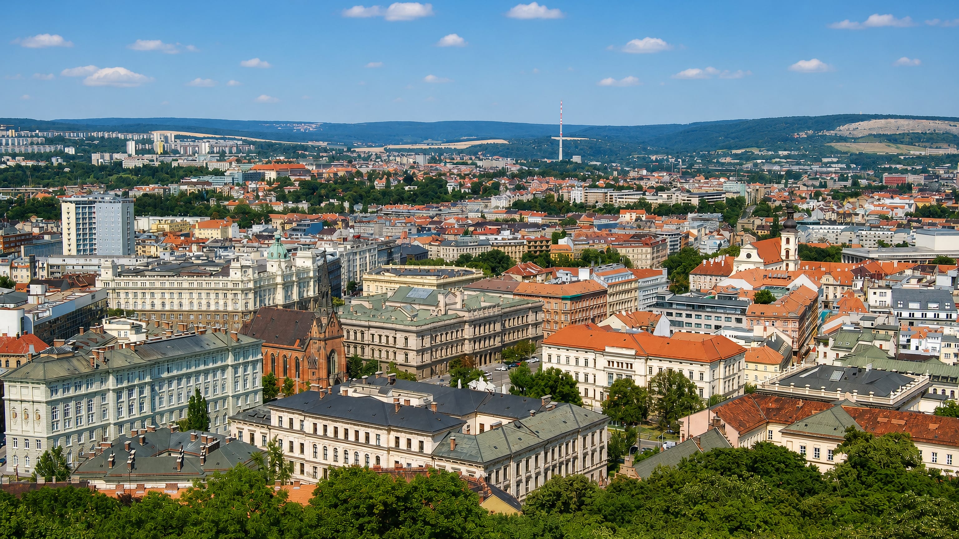 Grand historic buildings and red roofs of Cerna Pole, Brno, with the city and wooded hills beyond