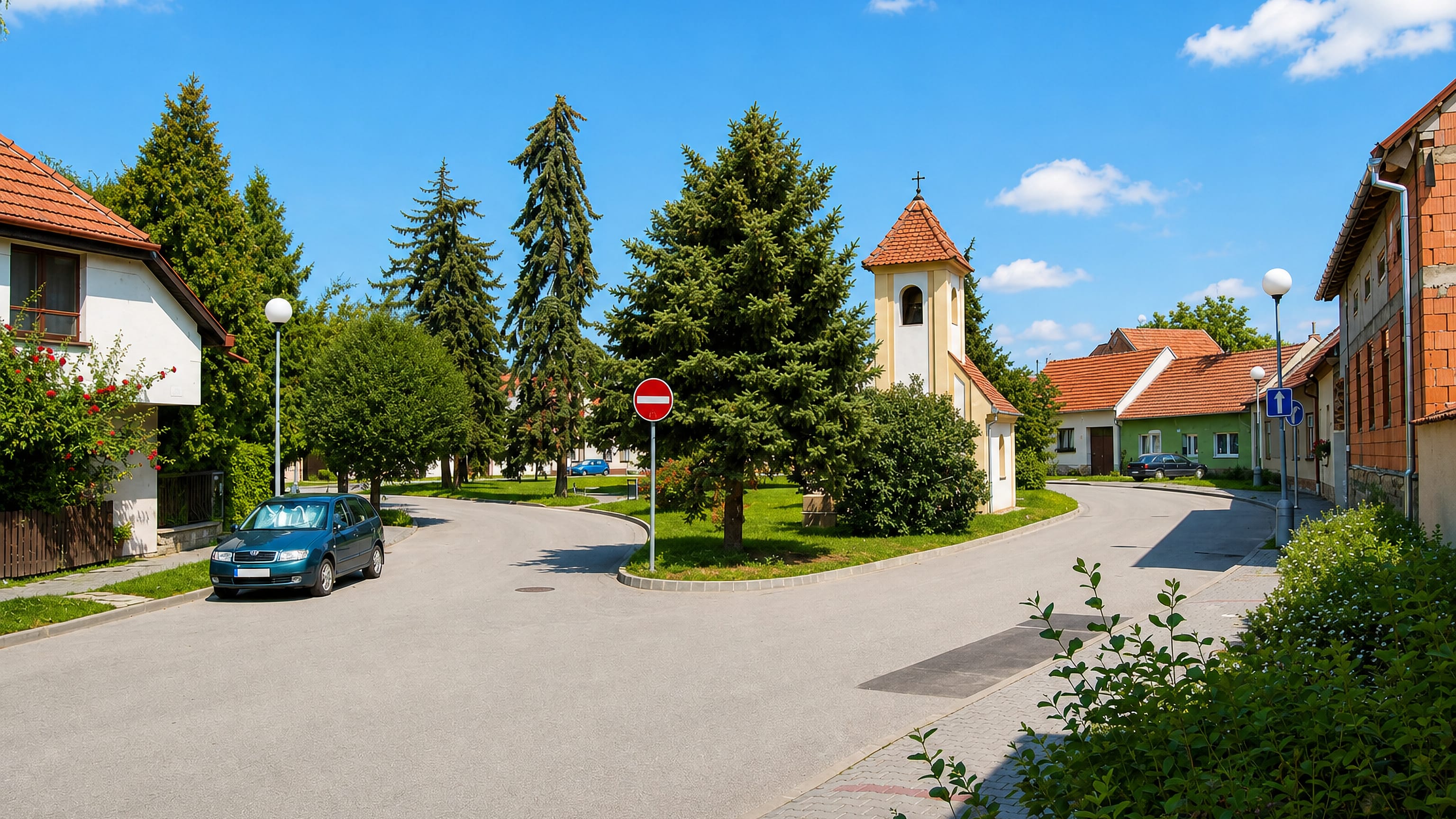 Village street with a small bell-tower chapel and spruce trees in Dolní Heršpice, Brno.