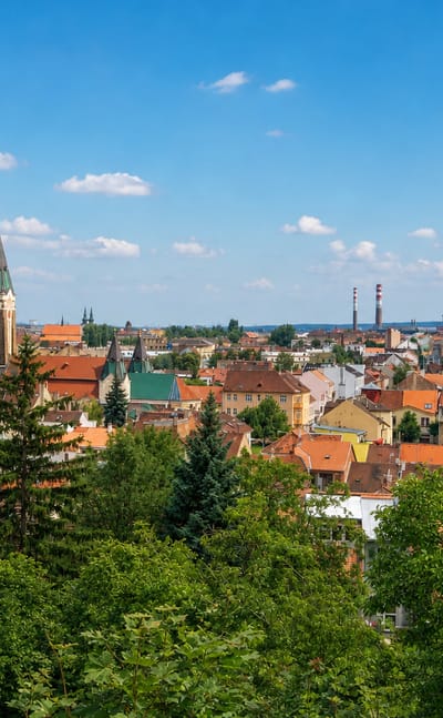 Red-tiled rooftops, a green church spire and industrial chimneys across Husovice in northern Brno.