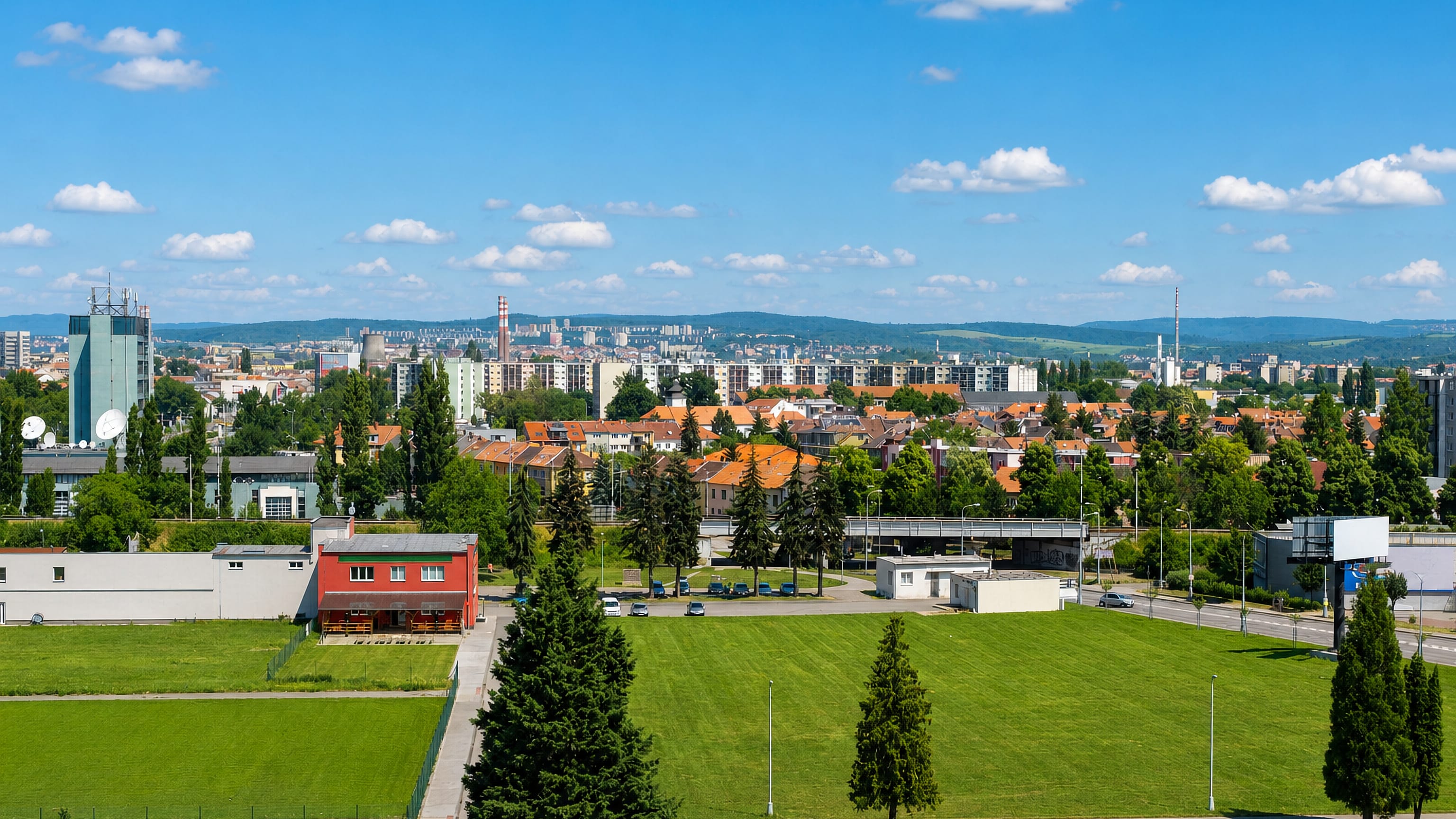 View across Komarov, Brno, over housing blocks and red-tiled roofs to wooded hills.