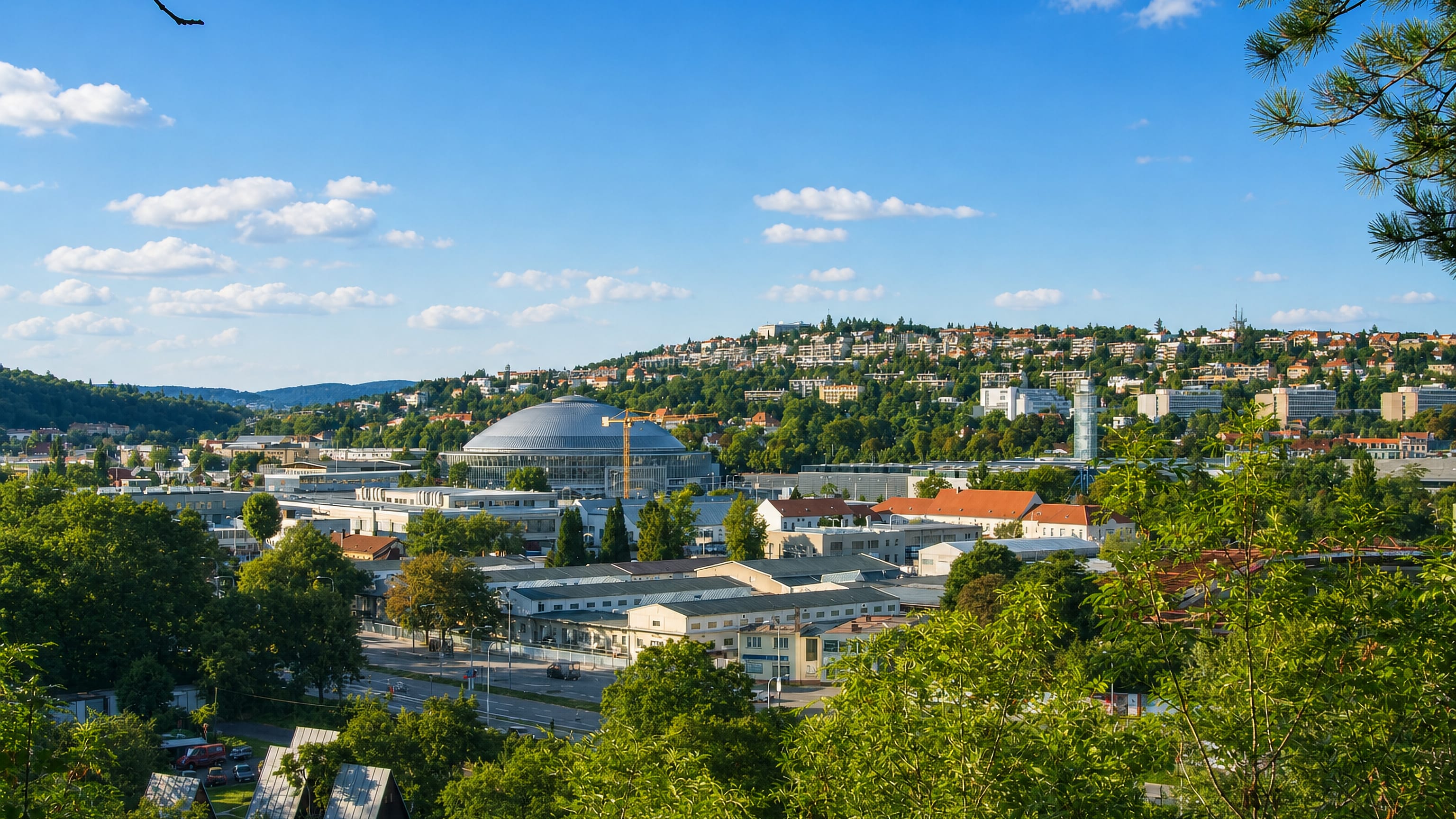 Pisarky in Brno seen from a wooded slope, the domed Pavilion A of the Brno Exhibition Centre at its heart.