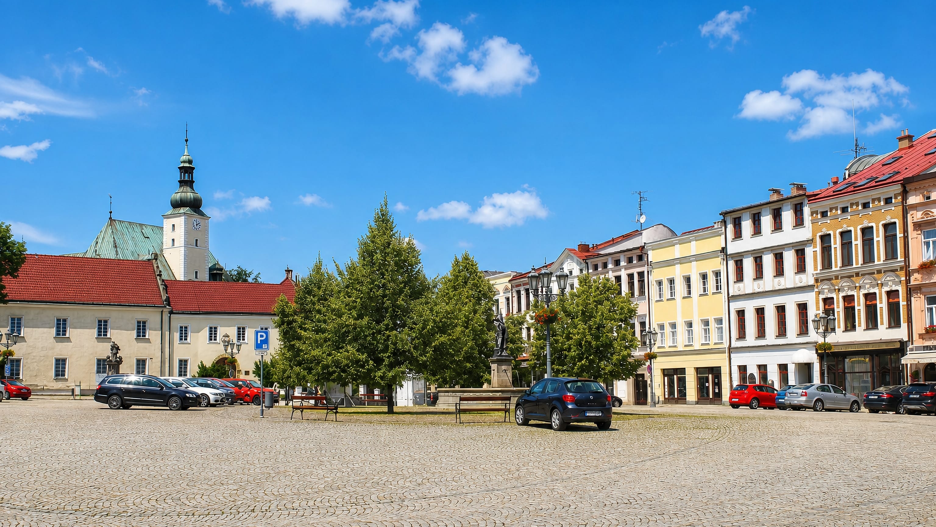 Cobbled main square of Frýdek-Místek, Czechia, lined with pastel burgher houses beneath a baroque church tower