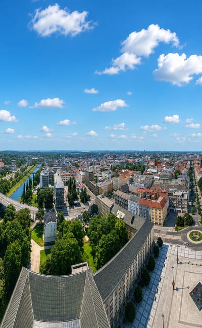 Panorama over Ostrava from the New City Hall tower, the Ostravice river curving past red-roofed streets.
