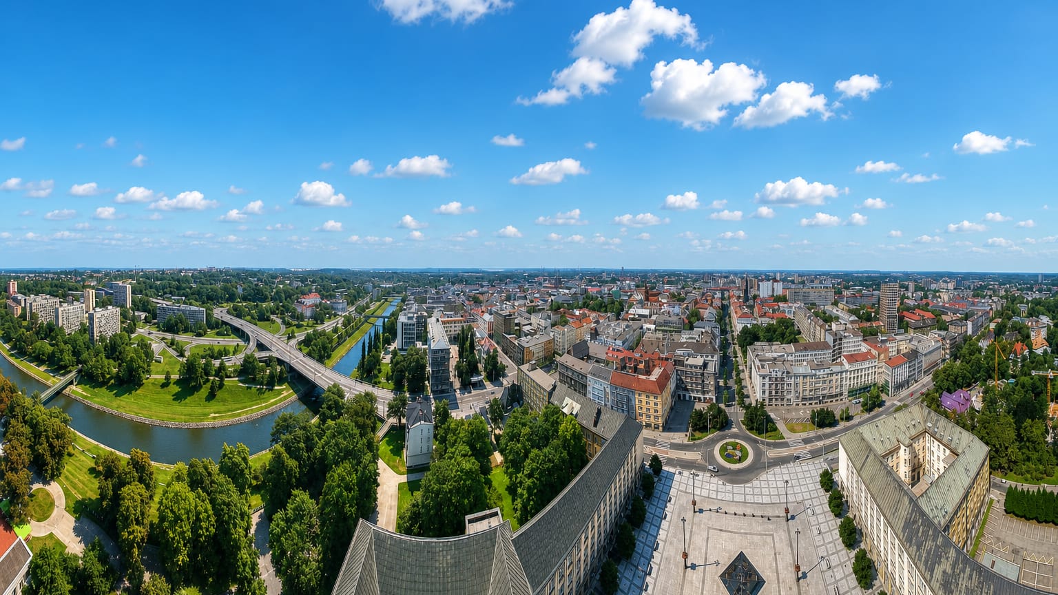 Panorama over Ostrava from the New City Hall tower, the Ostravice river curving past red-roofed streets.