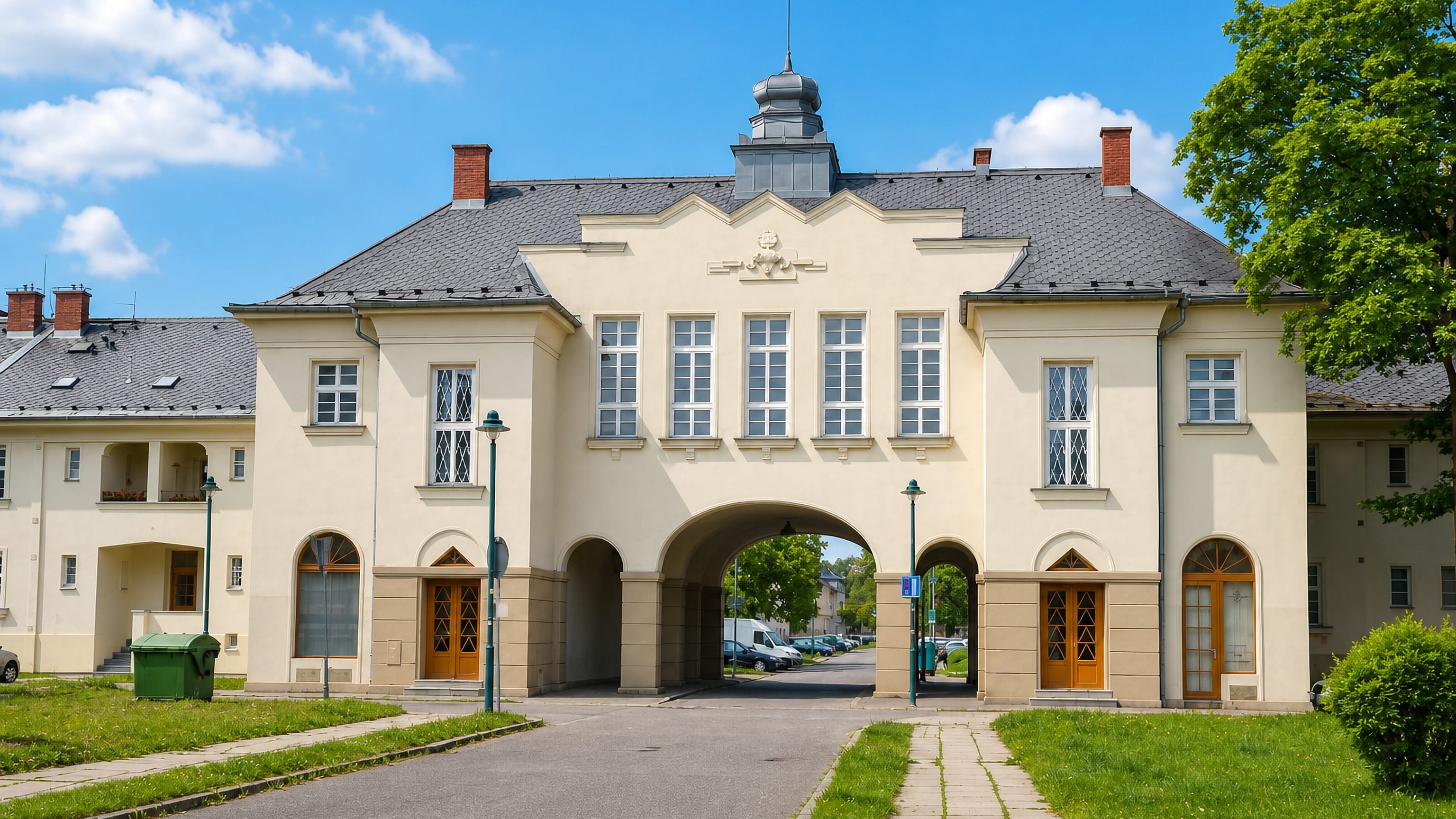 Arched gateway building of an interwar housing estate in Hrabuvka, Ostrava, under a blue summer sky.