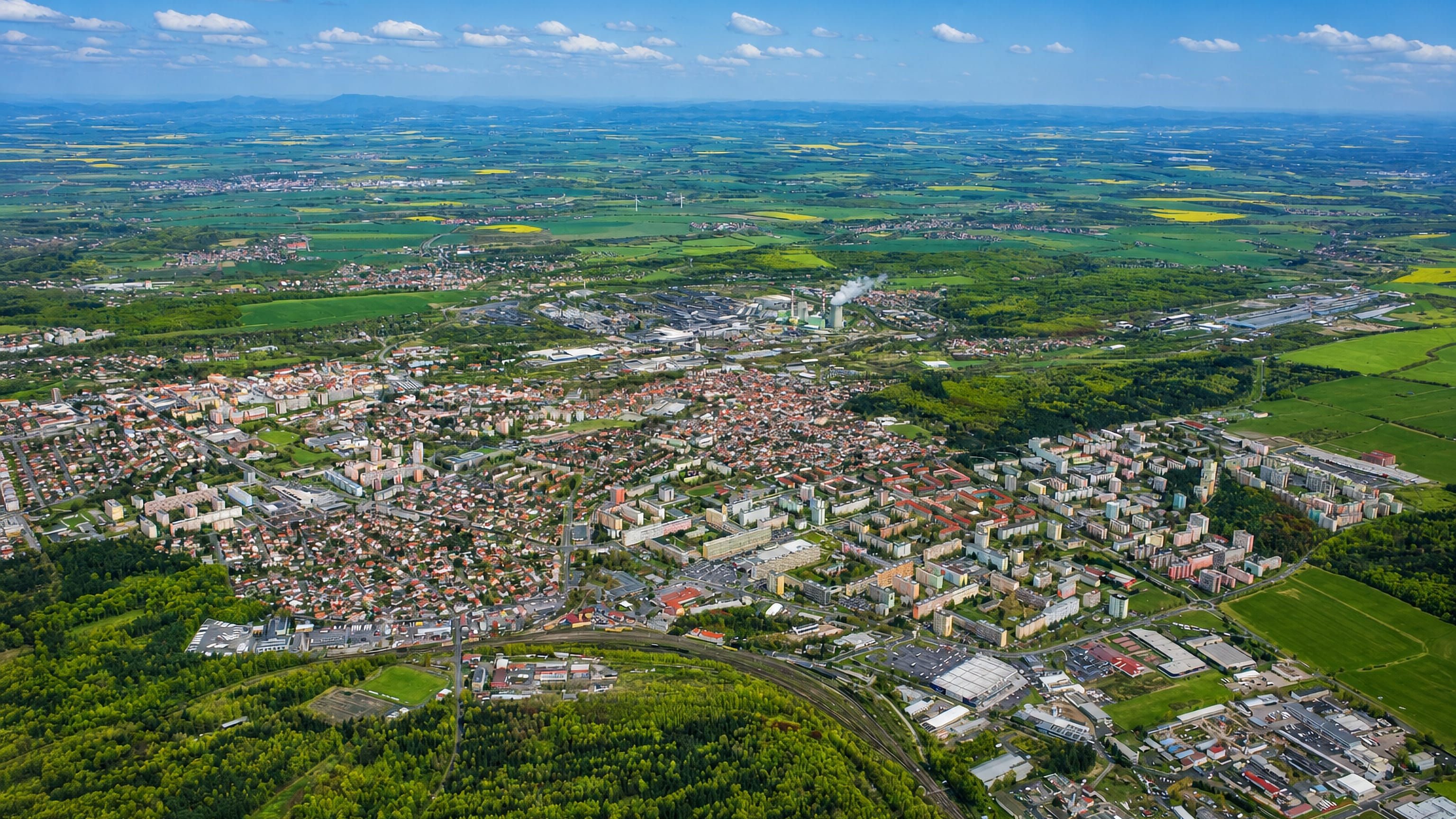 Aerial view over Dubi and Kladno, showing housing blocks, industry and Central Bohemian farmland beyond.