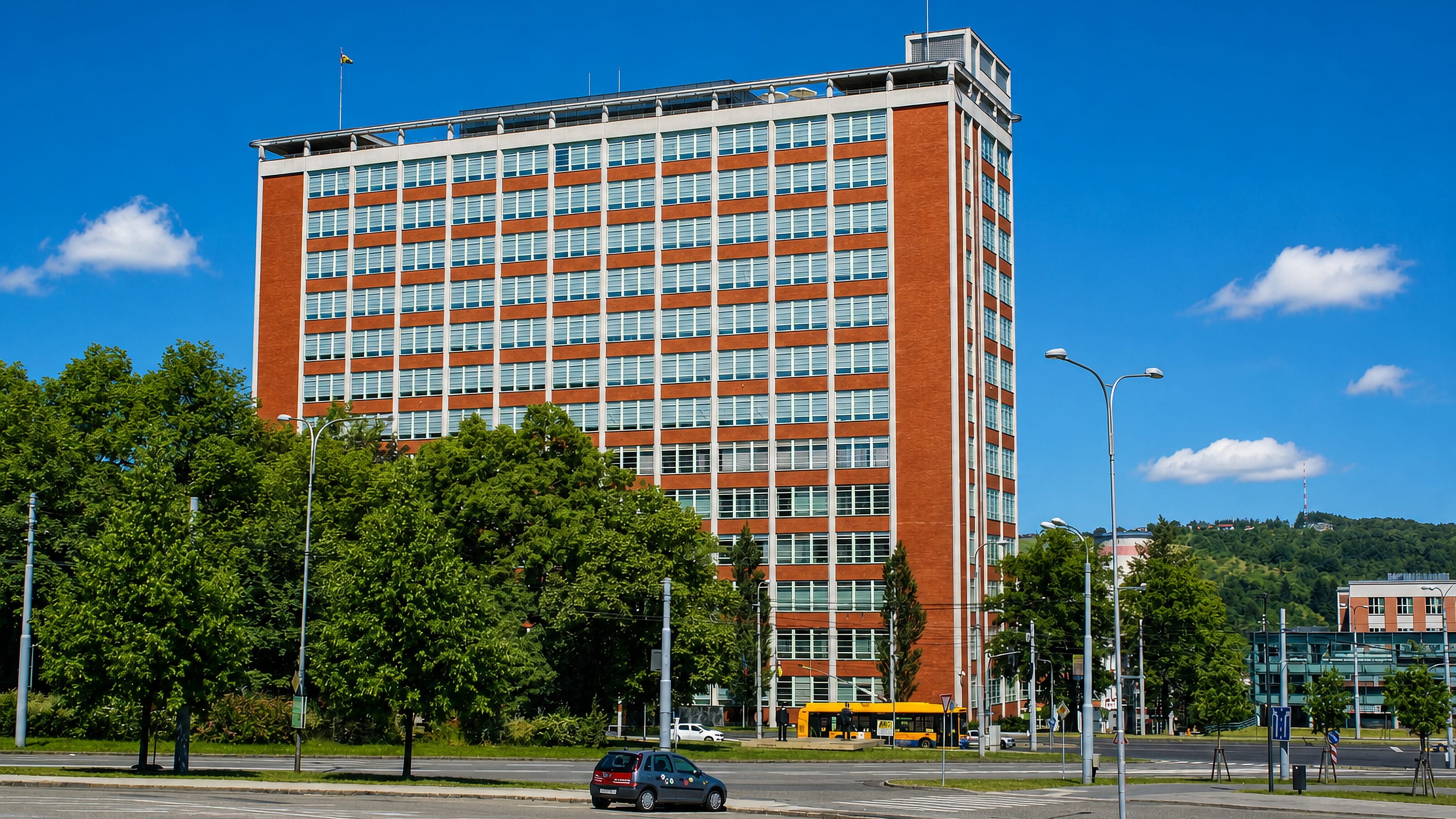 The red-brick Bata Skyscraper towering over Zlín, Czechia, with wooded hills rising behind the town