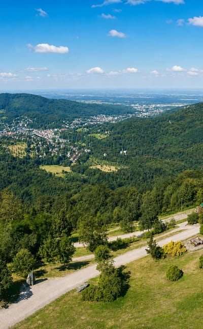 Baden-Baden nestled in a forested Black Forest valley seen from a wooded hilltop overlook.