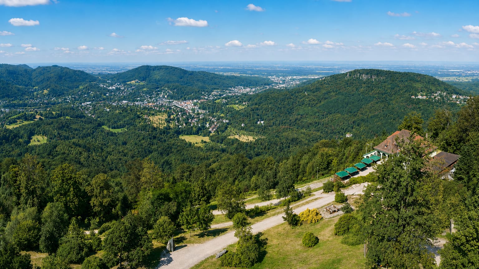 Baden-Baden nestled in a forested Black Forest valley seen from a wooded hilltop overlook.