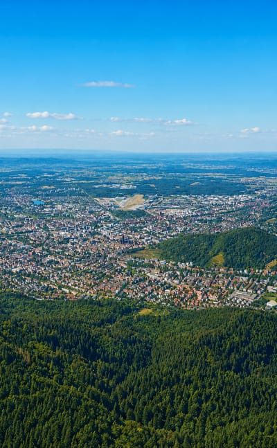Distant aerial of Freiburg im Breisgau spread across its valley at the forested edge of the Black Forest.