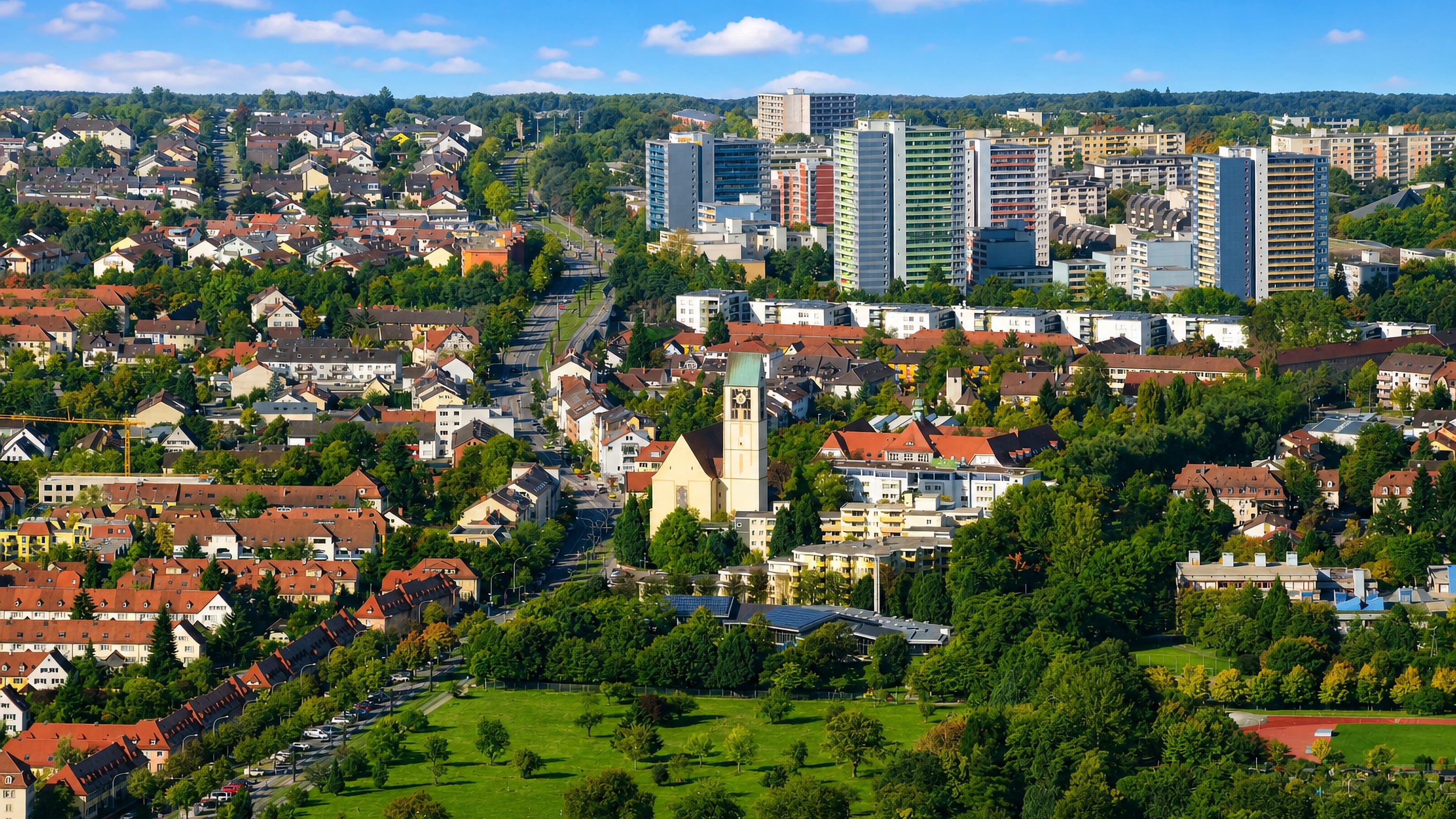 Haslach in Freiburg seen from above, its church tower and low roofs backed by the Weingarten high-rises.