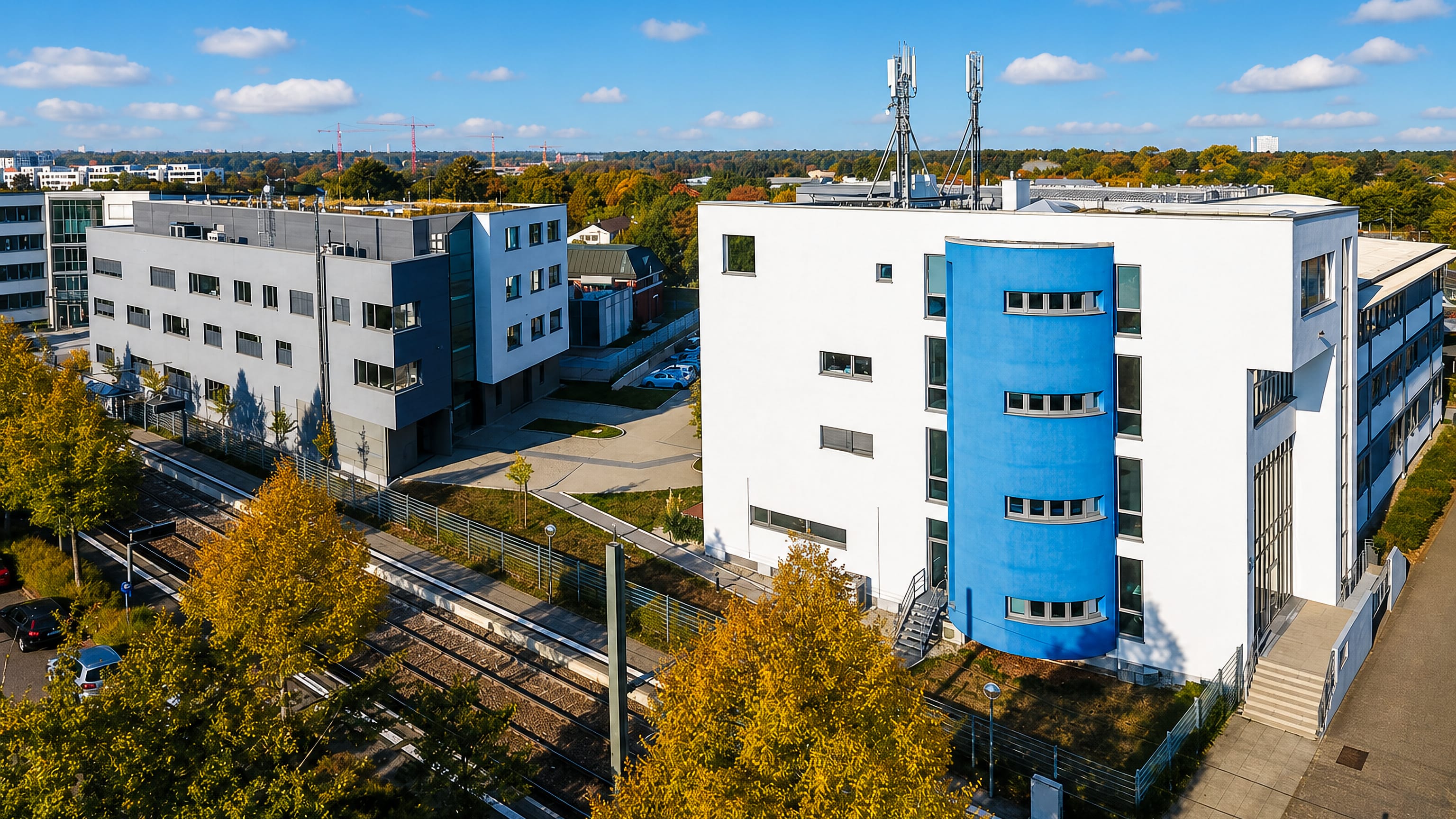 Modern office buildings with a blue stair tower beside tram tracks in Hagsfeld, a district of Karlsruhe.