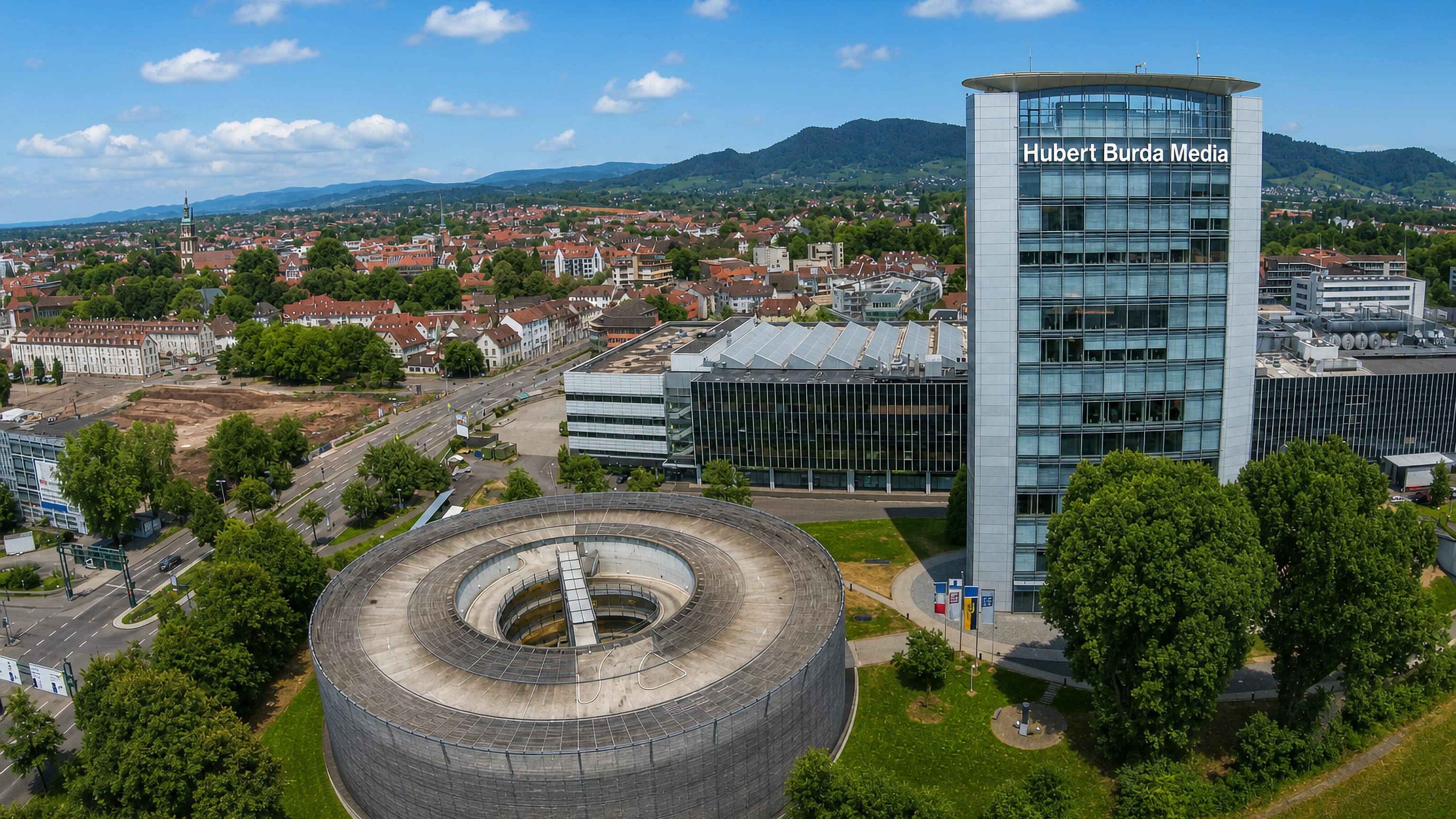 Offenburg's Burda Media tower and round concrete hall above the old town, with Black Forest hills behind.
