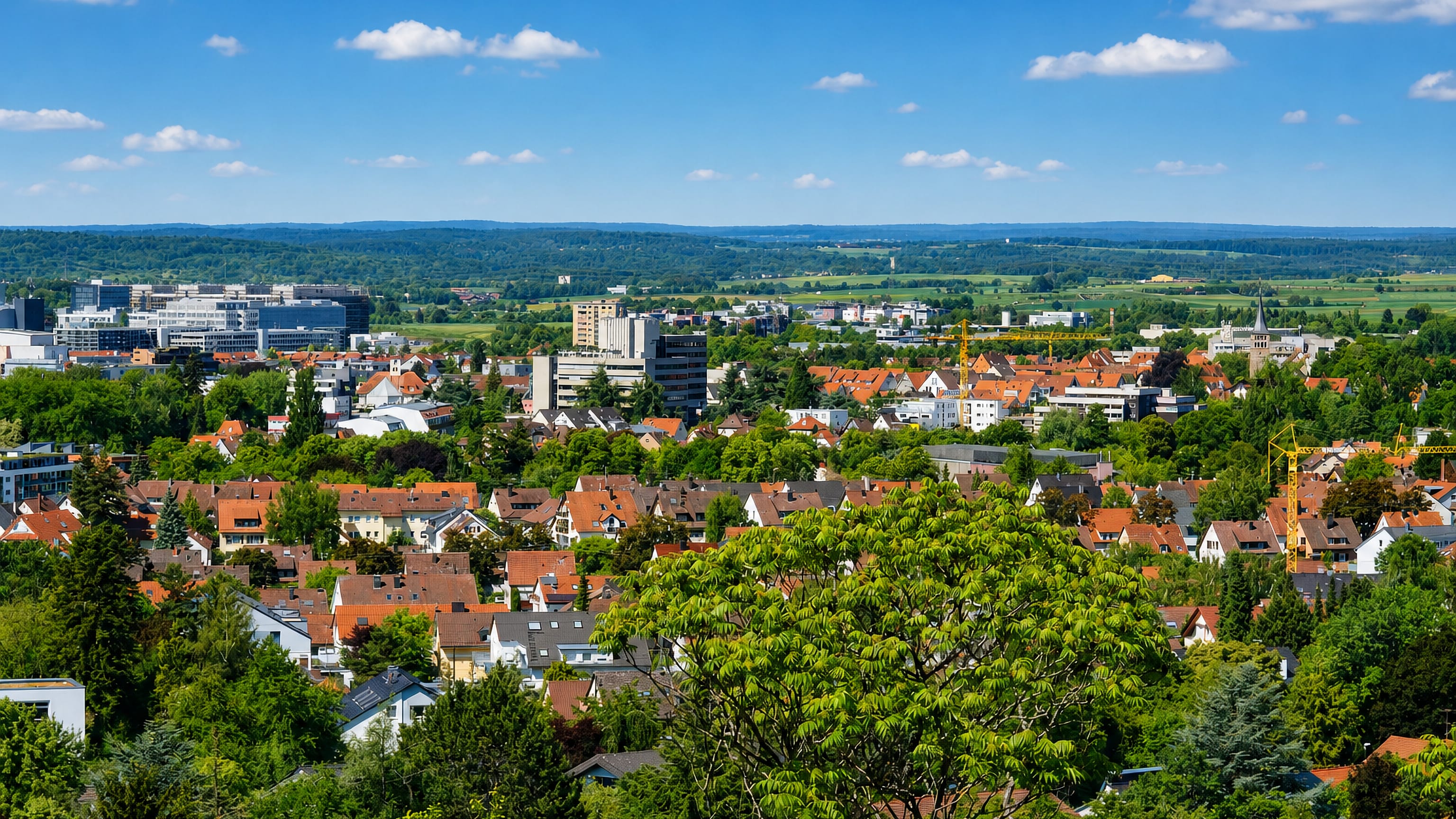 Sindelfingen, Germany, viewed from a wooded hill: red-tiled houses, office blocks and open countryside beyond