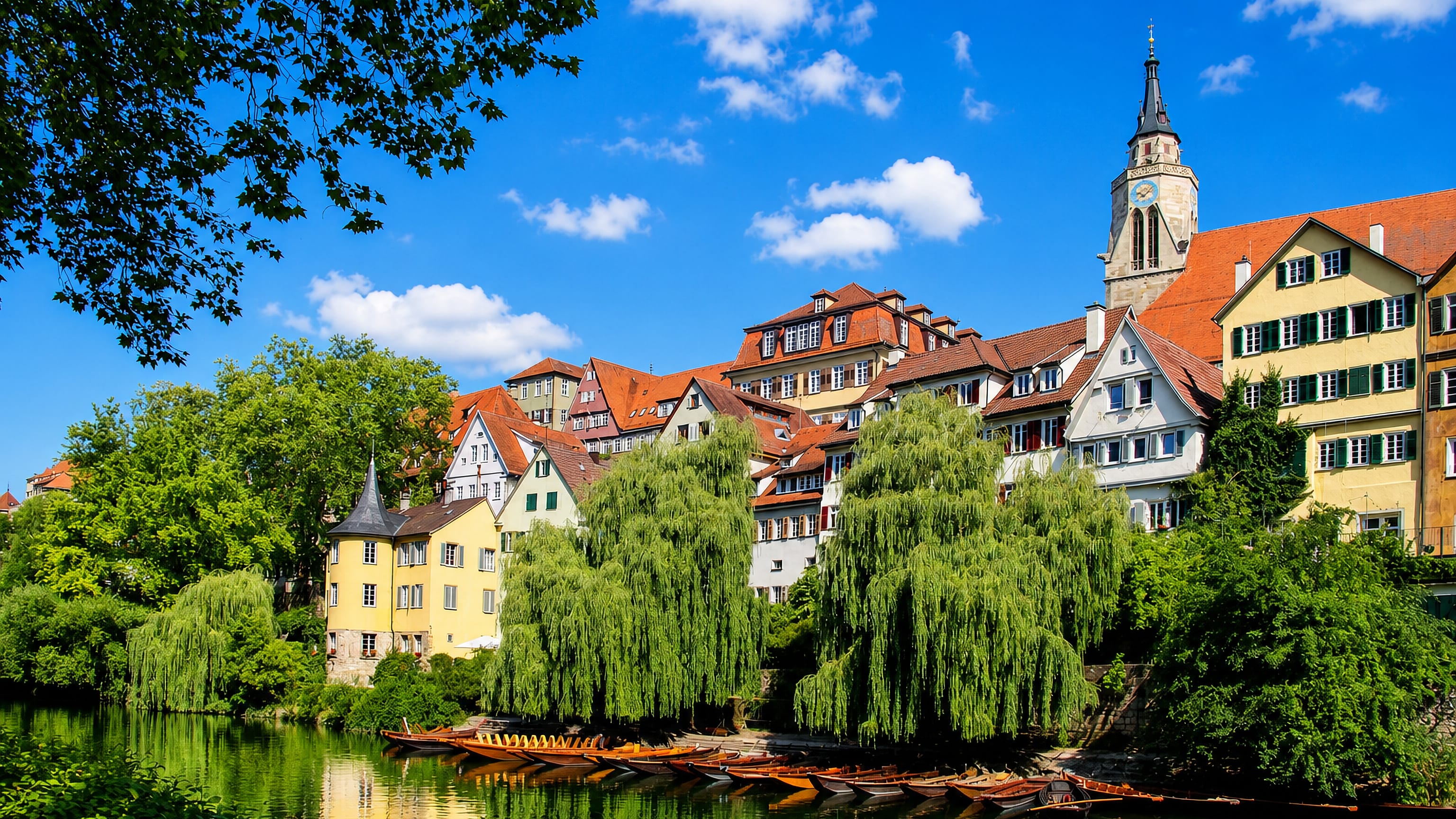 Tübingen's Neckarfront: pastel old-town houses, the Hölderlinturm and Stiftskirche spire above moored punts.