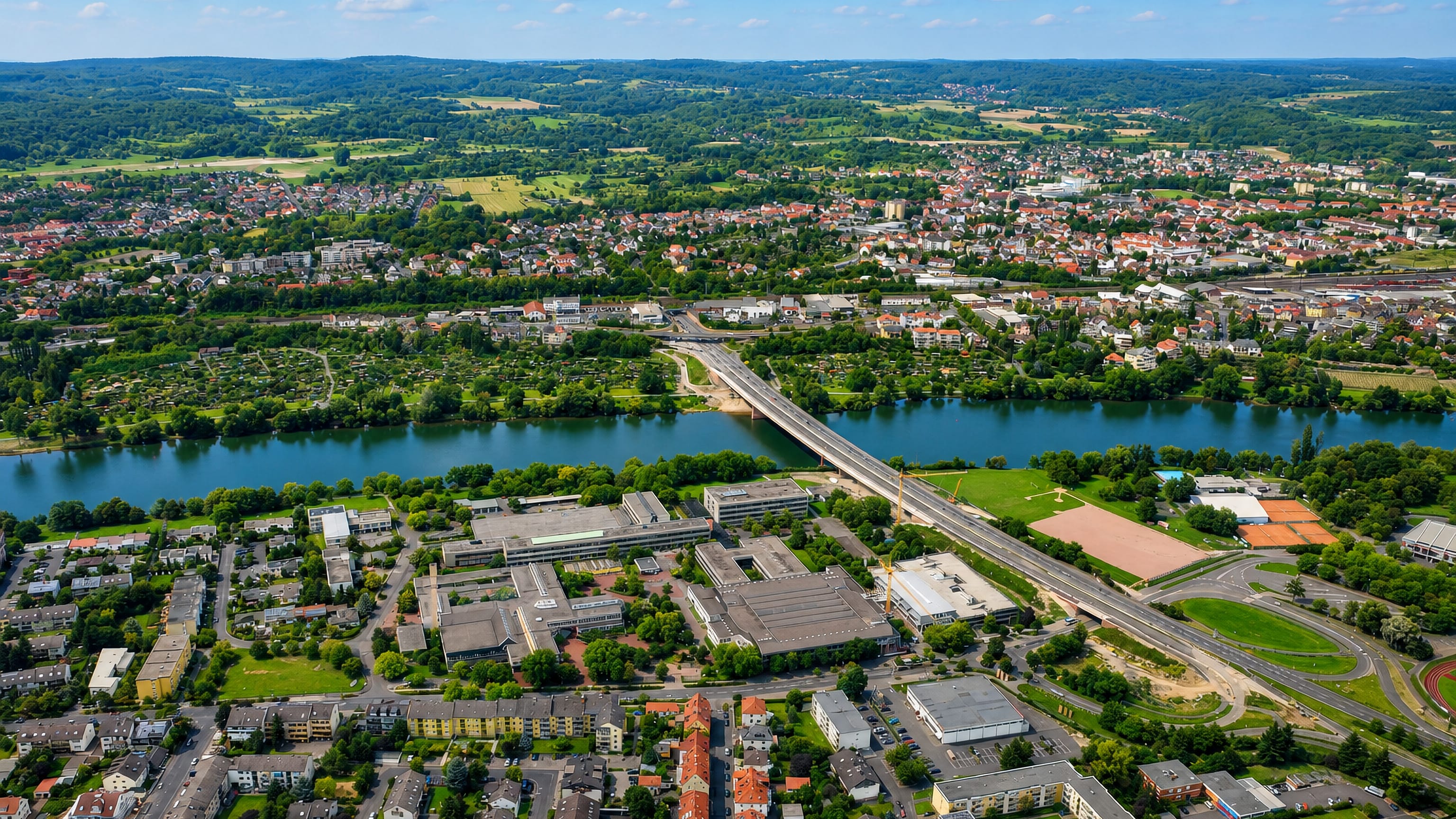 Aerial view over Damm in Aschaffenburg, spanning the River Main bridge to the Spessart hills beyond.