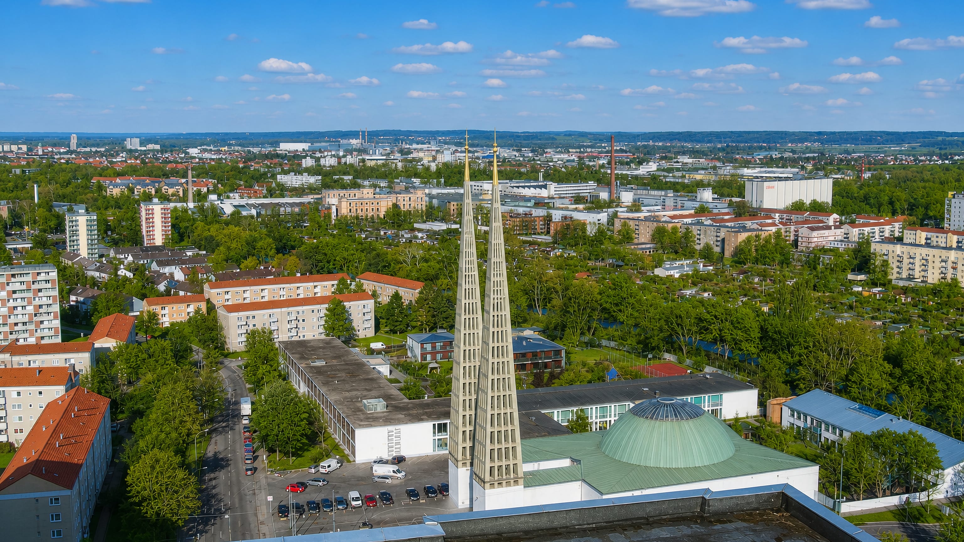 Aerial view over Spickel-Herrenbach in Augsburg, twin church spires and a green copper dome above leafy housing