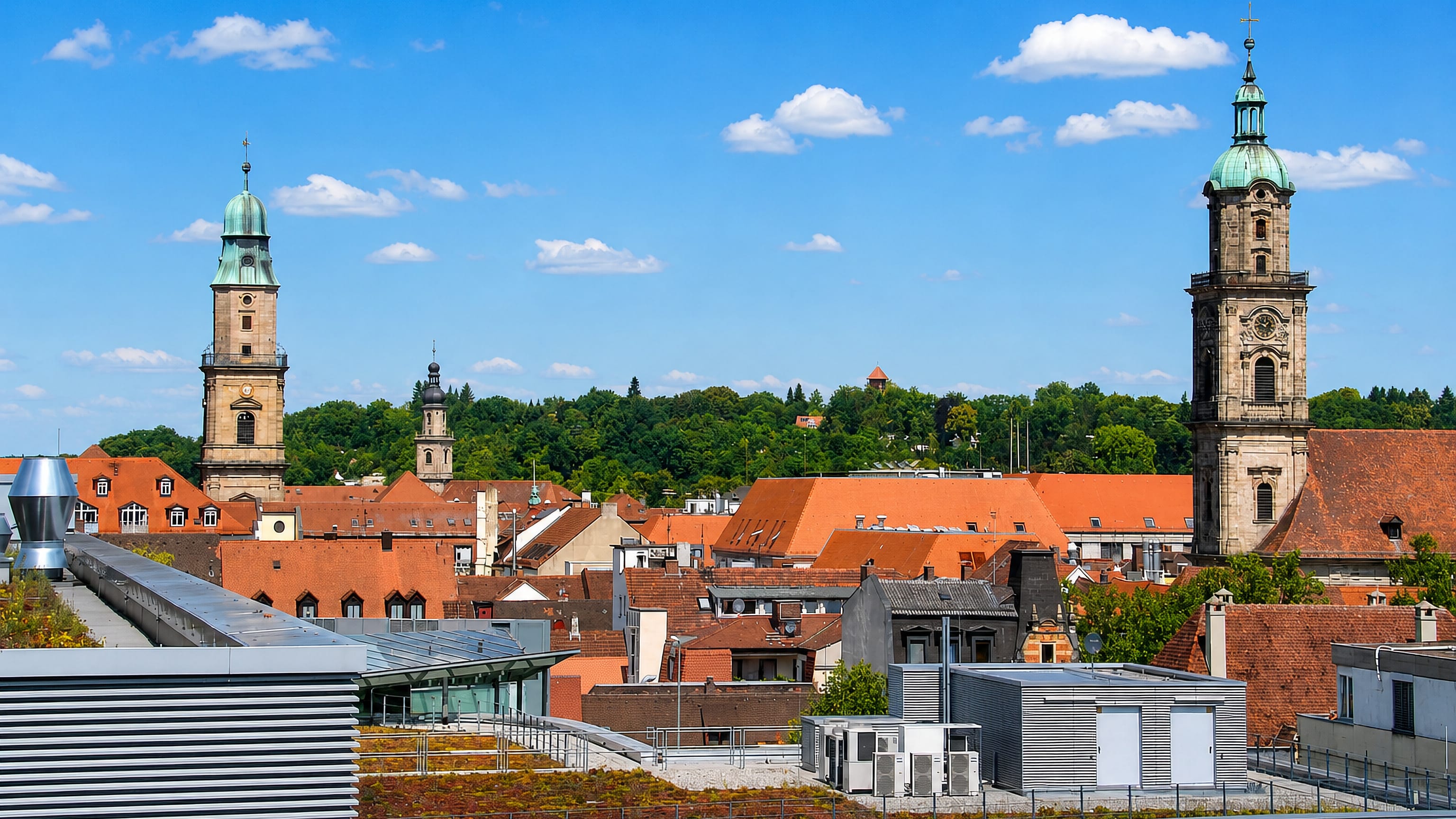 Baroque church towers with green copper domes above the red-tiled rooftops of Erlangen, Bavaria.