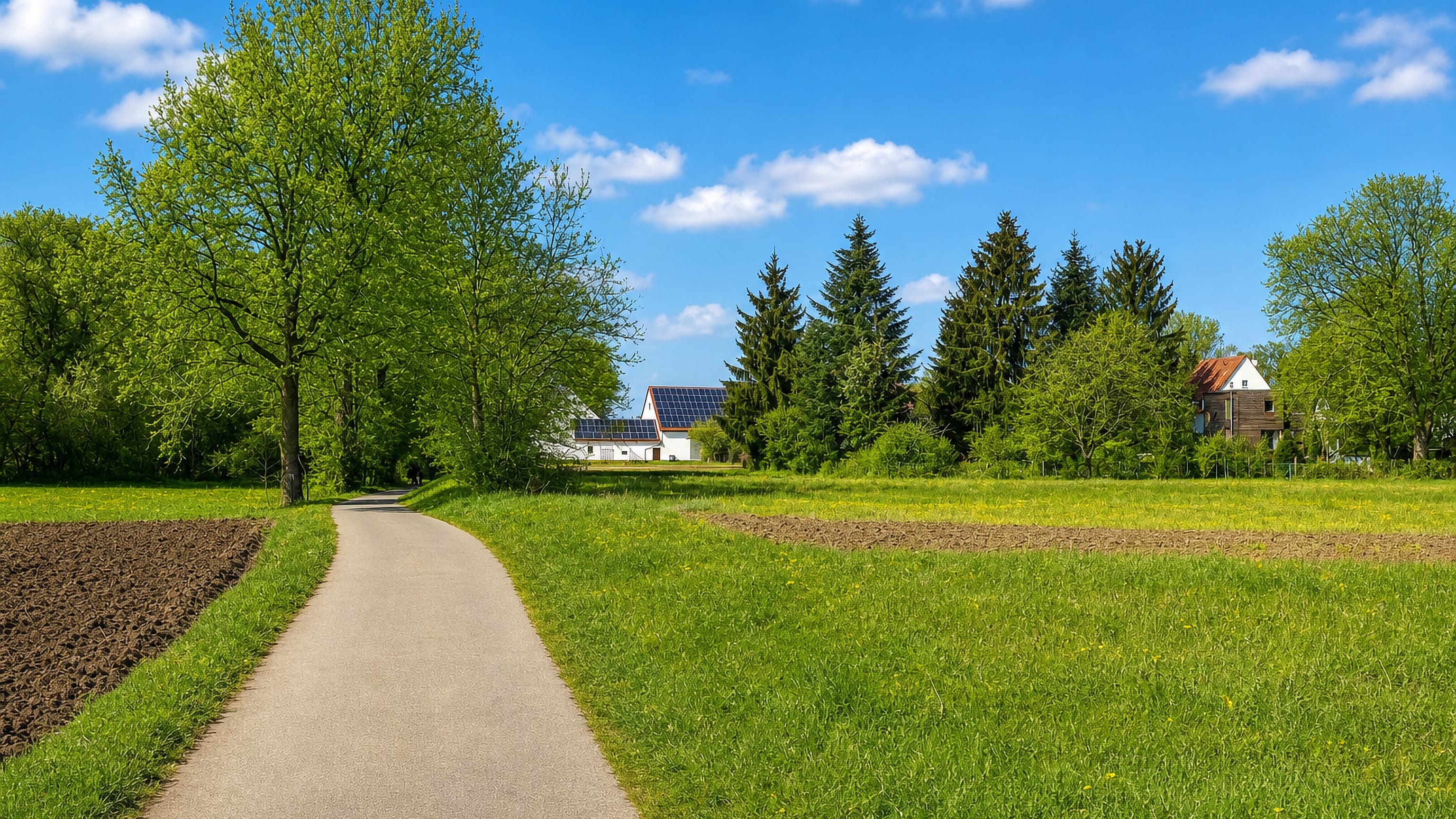 Country lane between fields leading to solar-panelled farmhouses at Weikershof on the edge of Fürth, Germany.